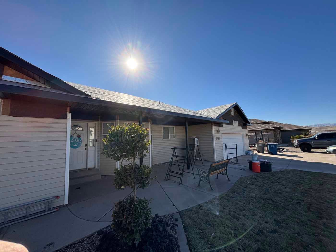 A house with a porch and a car parked in front of it on a sunny day.