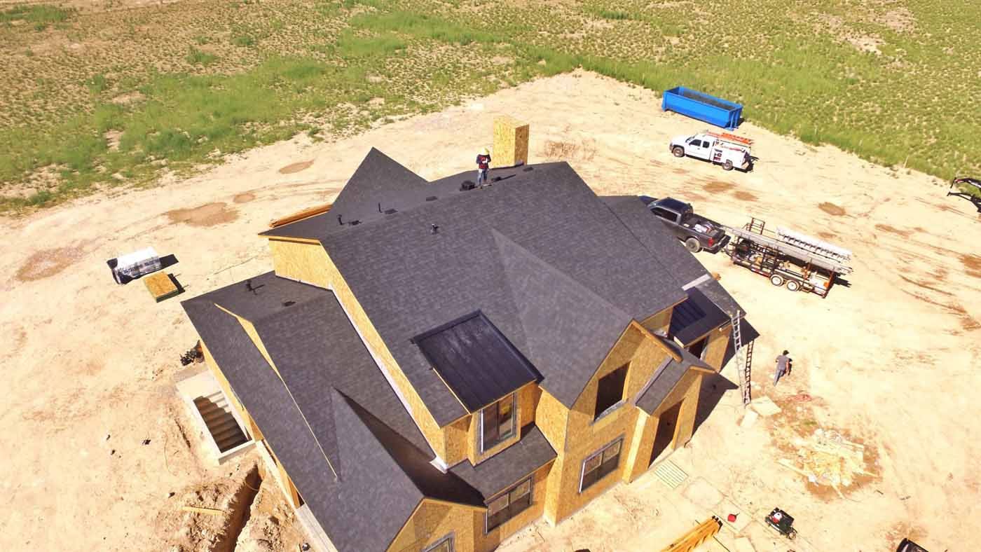 An aerial view of a house under construction in a dirt field.