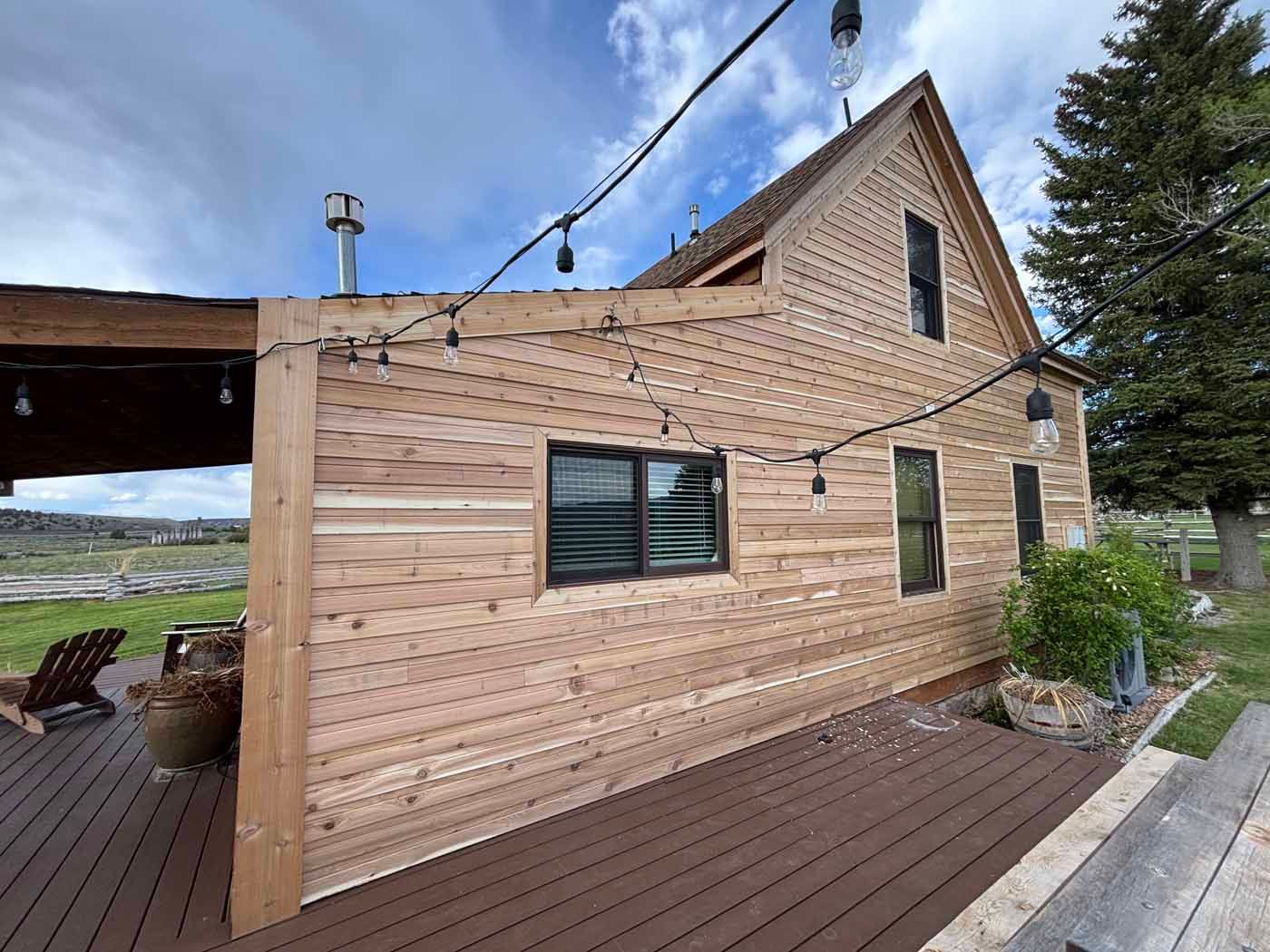 A wooden house with a wooden deck in front of it.
