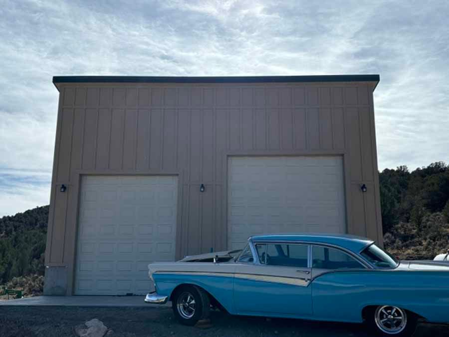 A blue car is parked in front of a garage.
