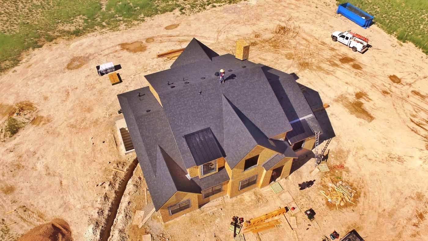 An aerial view of a house under construction in a dirt field.