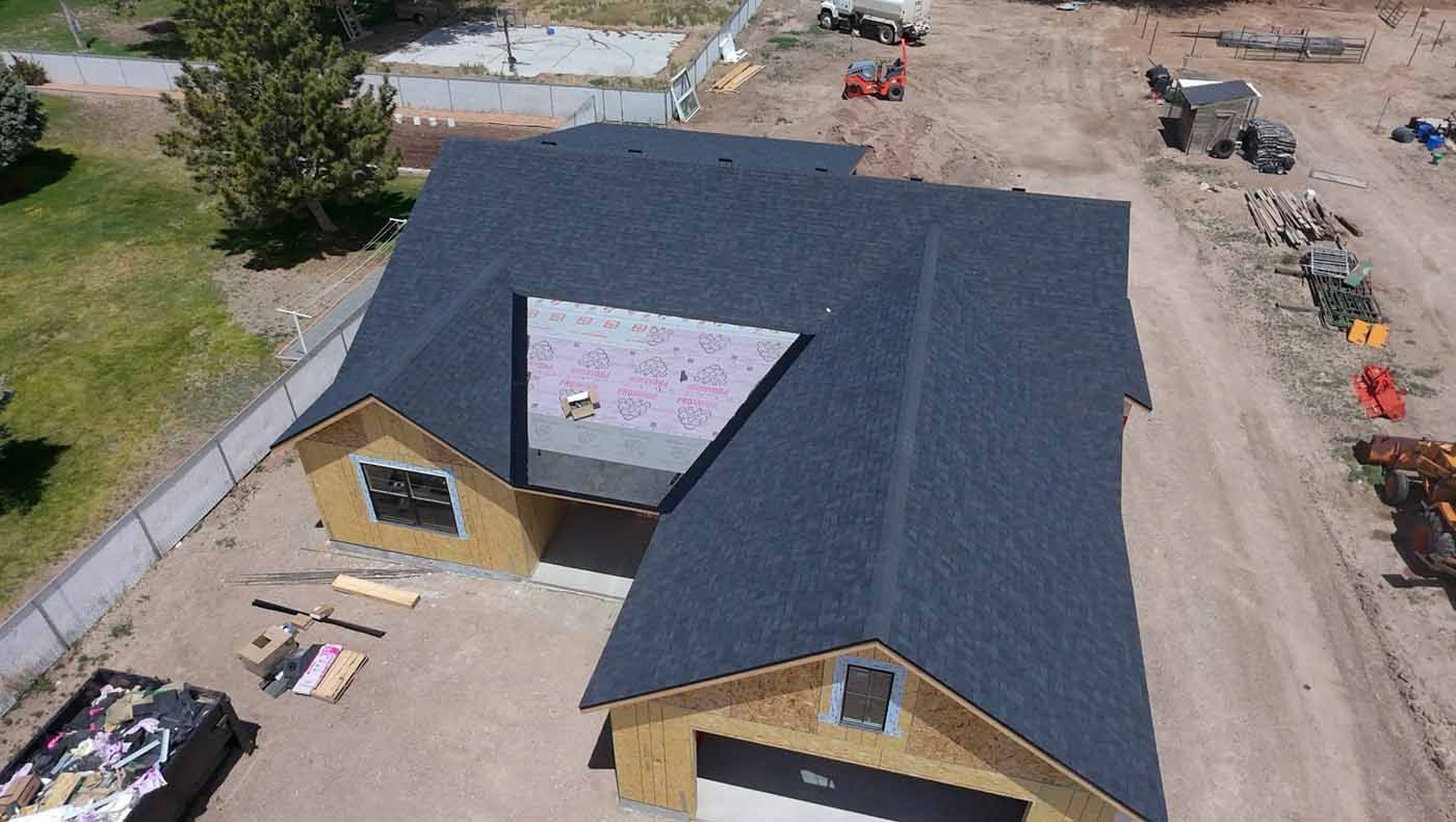 An aerial view of a house under construction with a black roof.