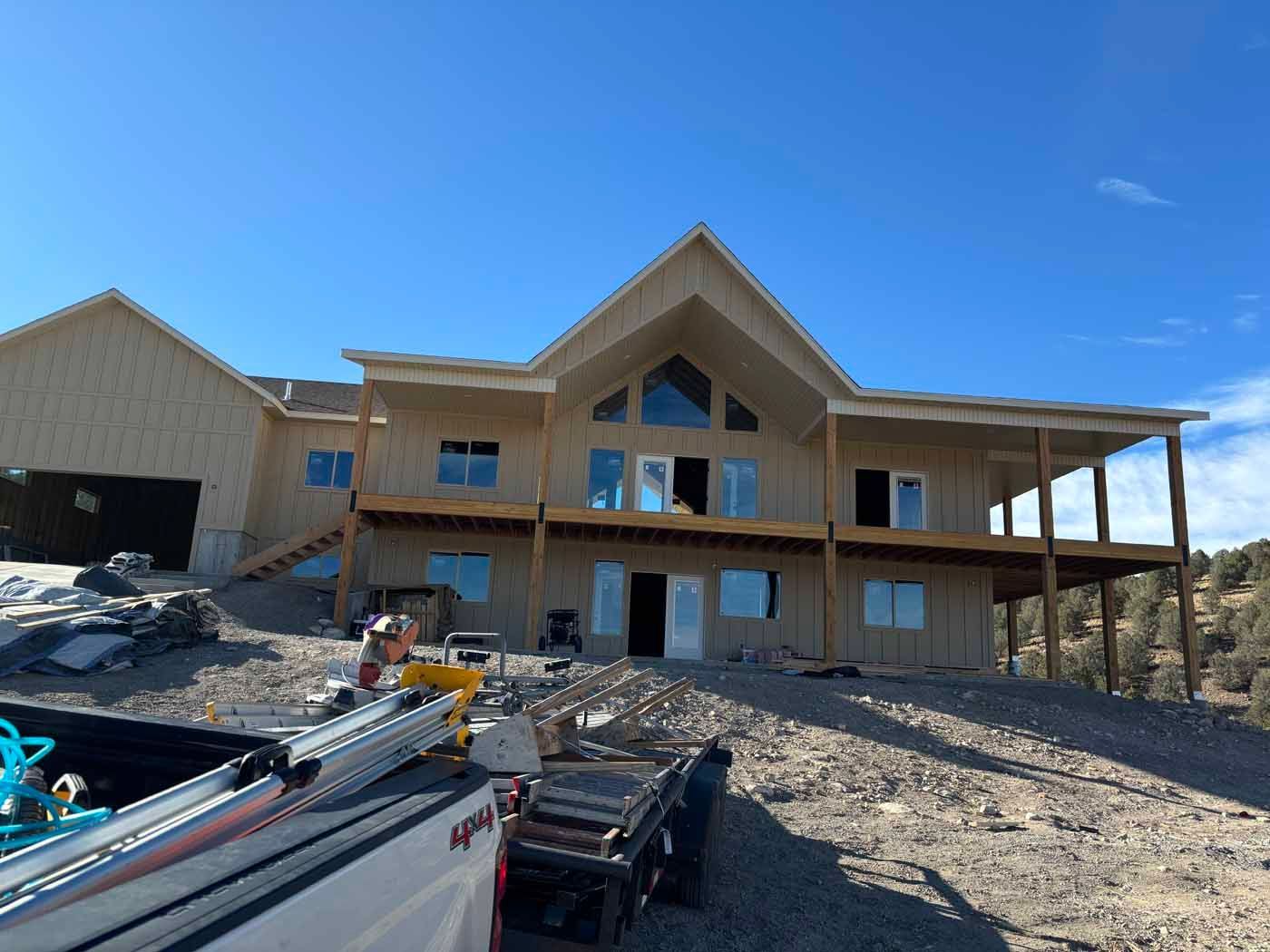 A large house is being built on top of a dirt hill.
