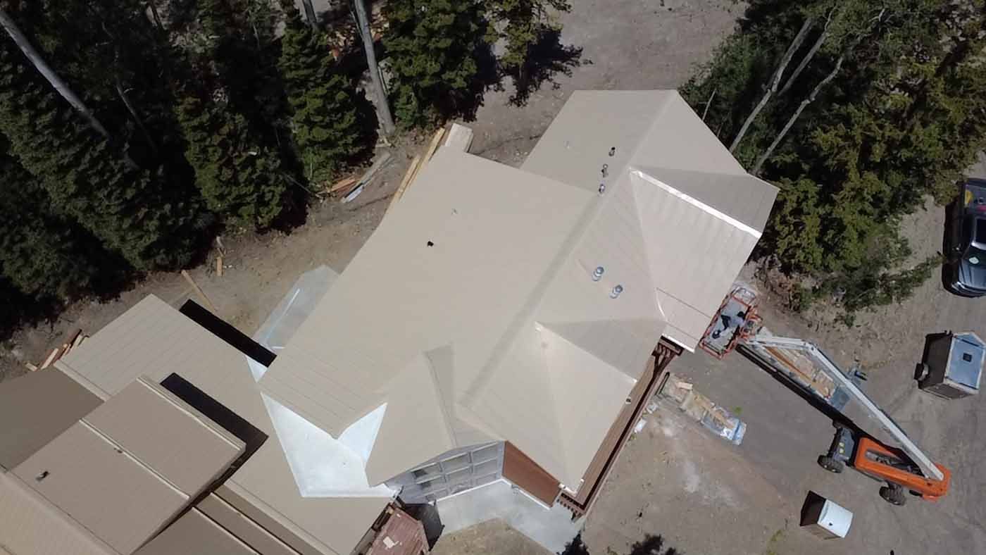 An aerial view of a house under construction with trees in the background.