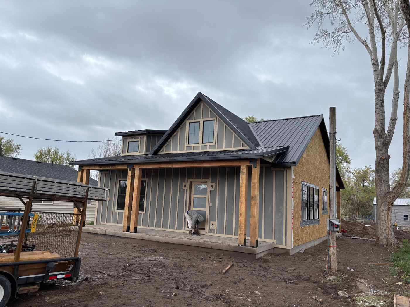 A small house is being built in the middle of a dirt field.