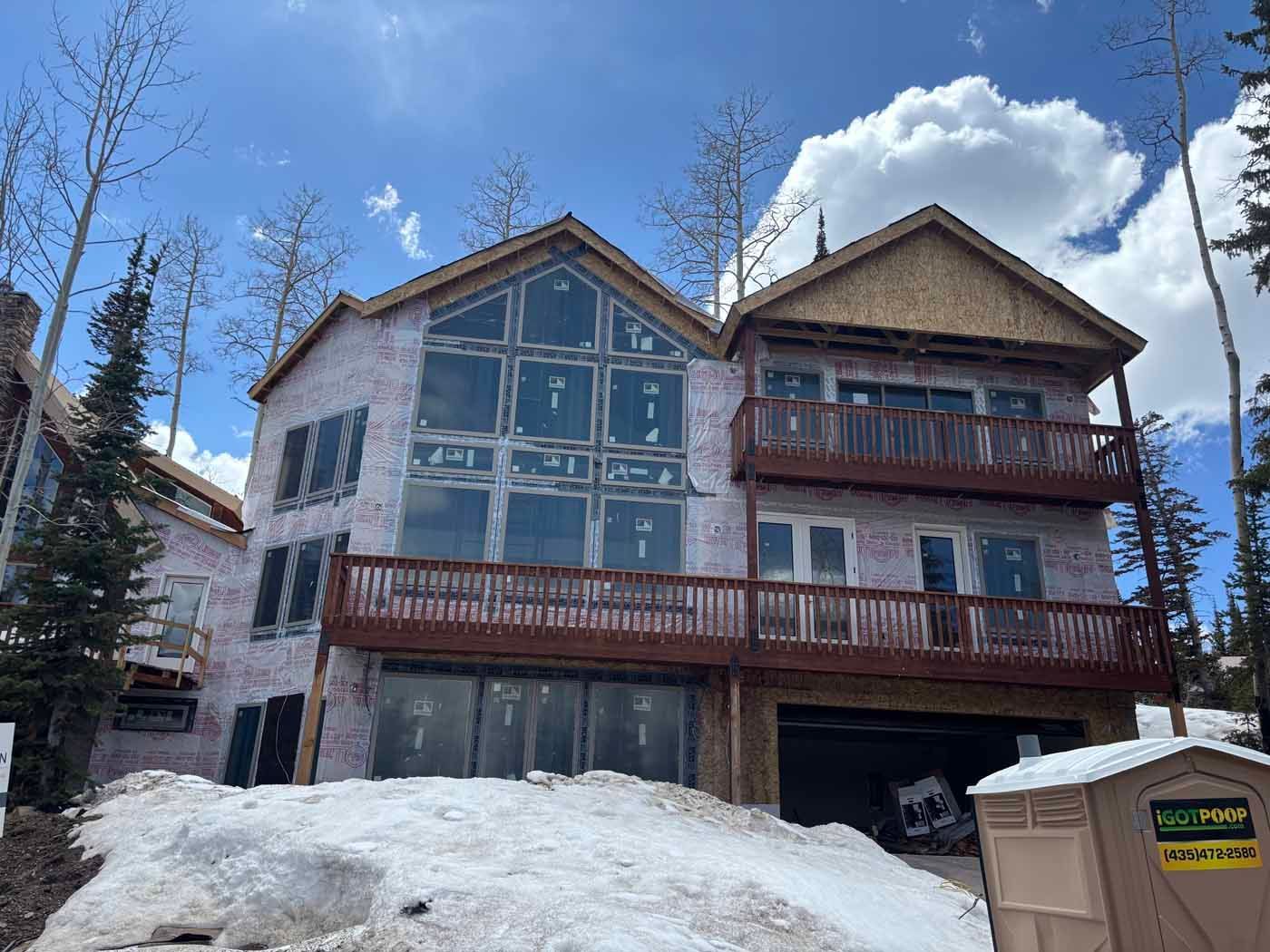 A large house is being built on top of a snow covered hill.