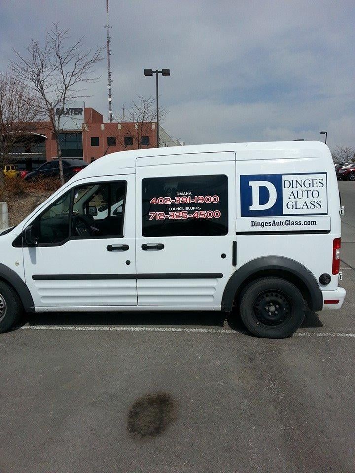 White van with Ding's Auto Glass logo parked in a lot, phone numbers displayed, black tires, cloudy sky.