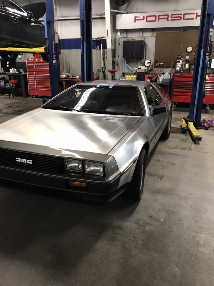 Silver DeLorean in a mechanic shop, with a 