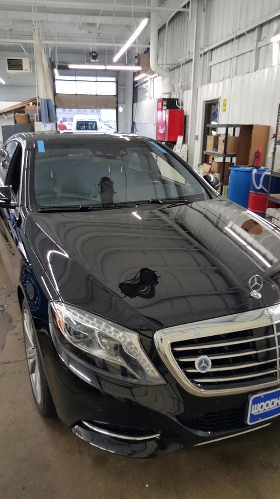 Black Mercedes sedan inside a garage. Silver trim, chrome grill, and blue dealer tag.
