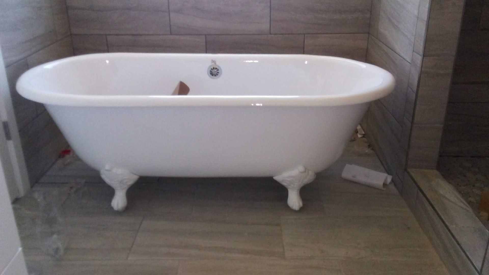 A white bathtub is sitting on a tiled floor in a bathroom.
