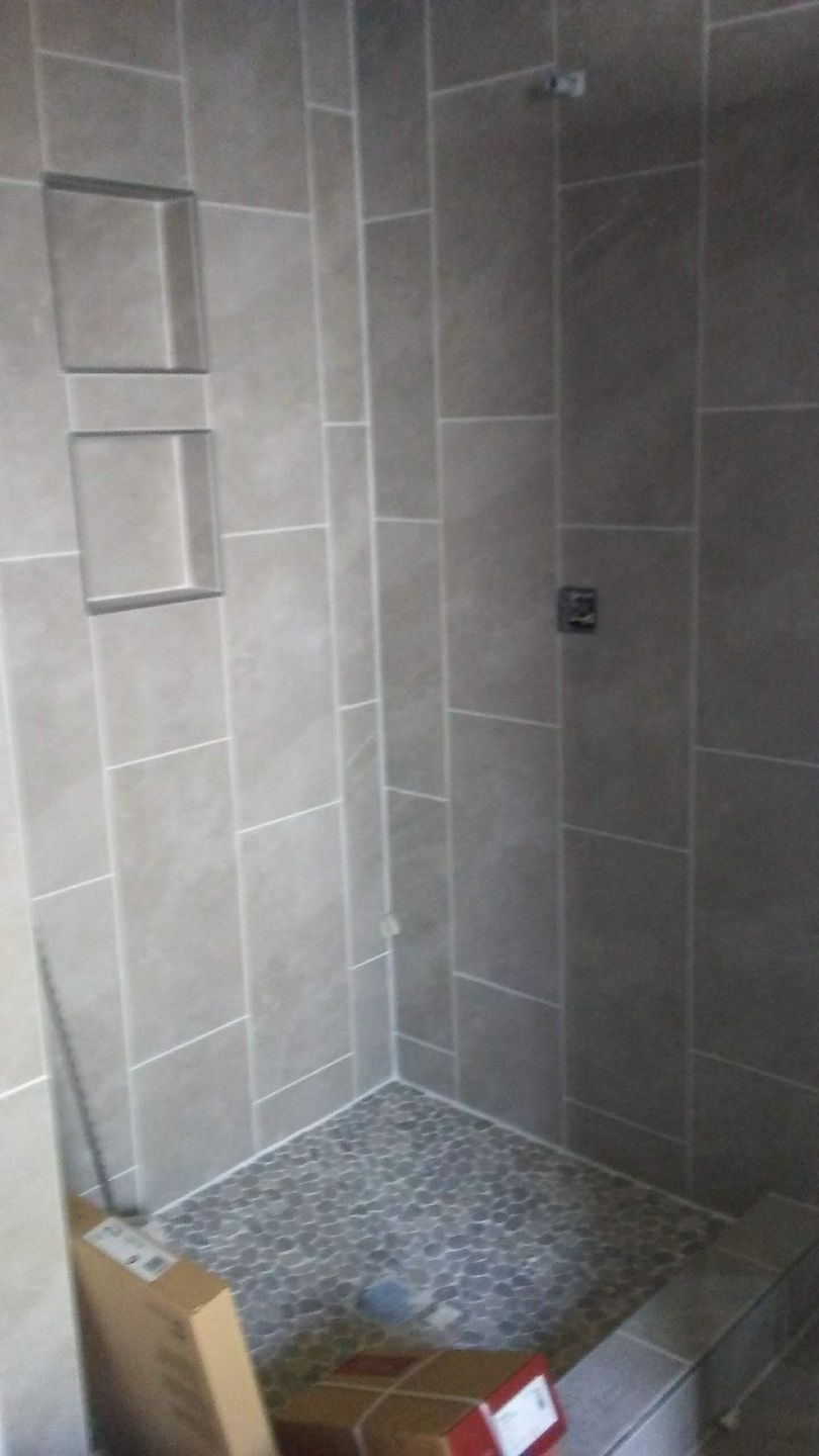 A bathroom with a walk in shower and a box on the floor.