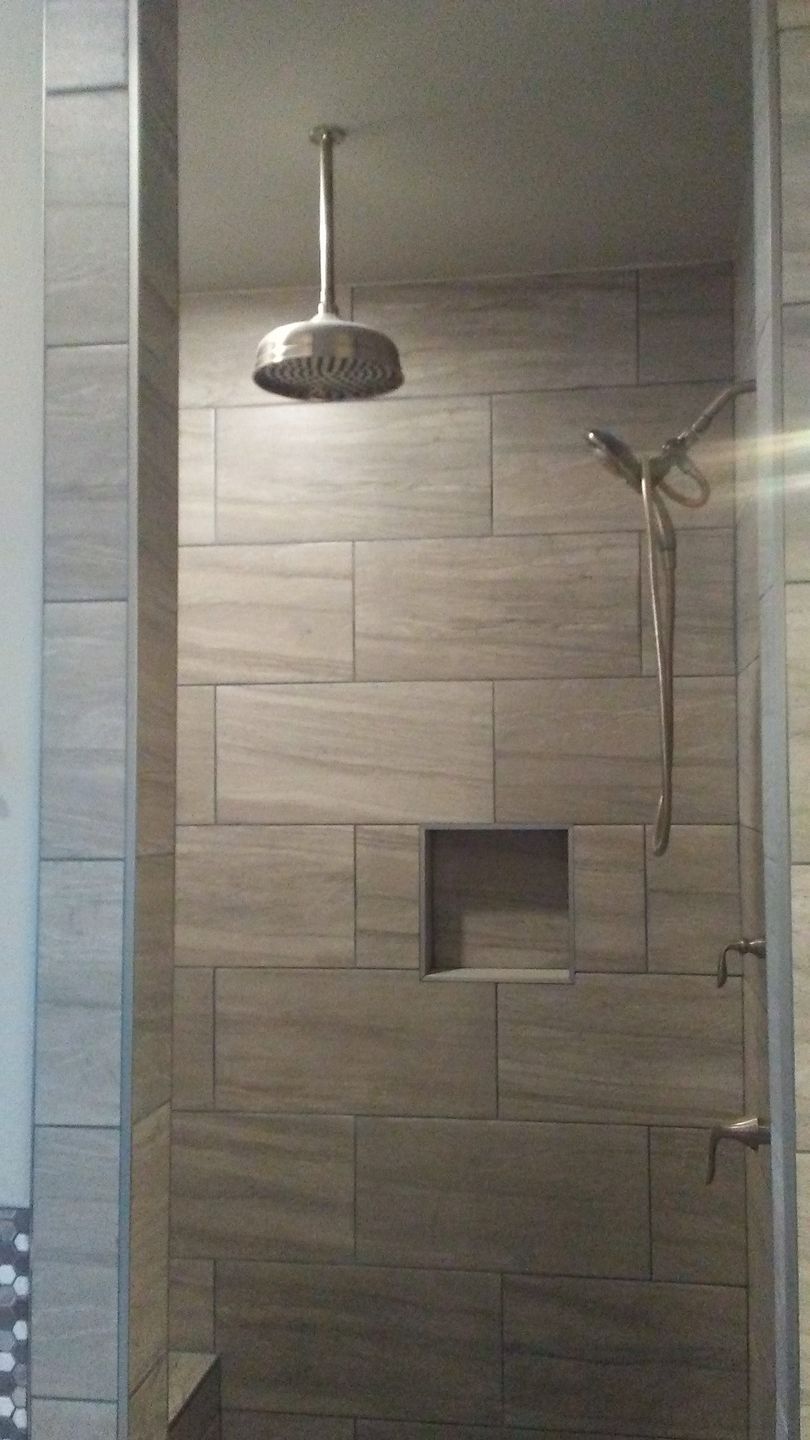 A shower with a ceiling mounted shower head in a bathroom.