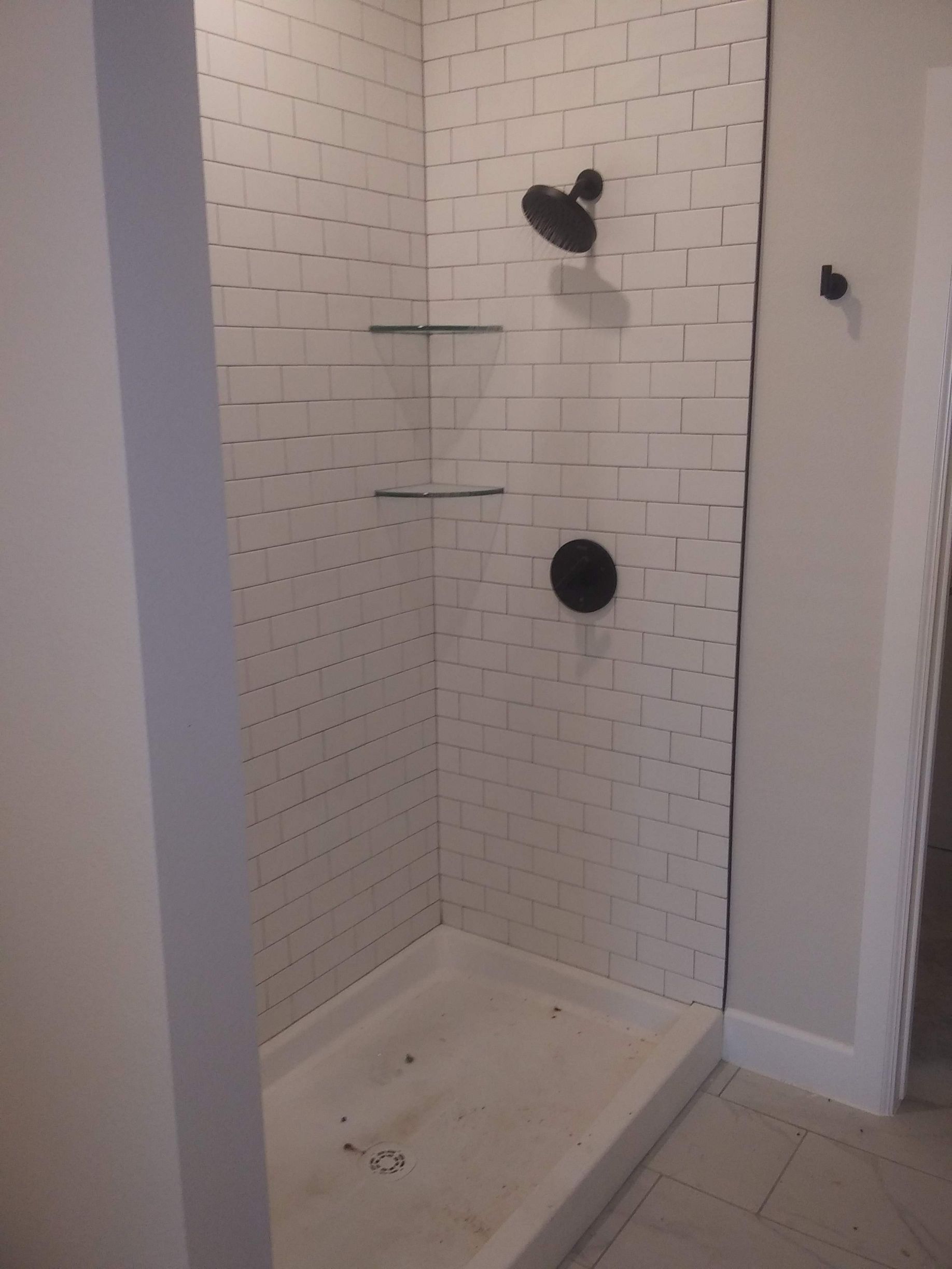 A bathroom with a walk in shower and a black shower head.