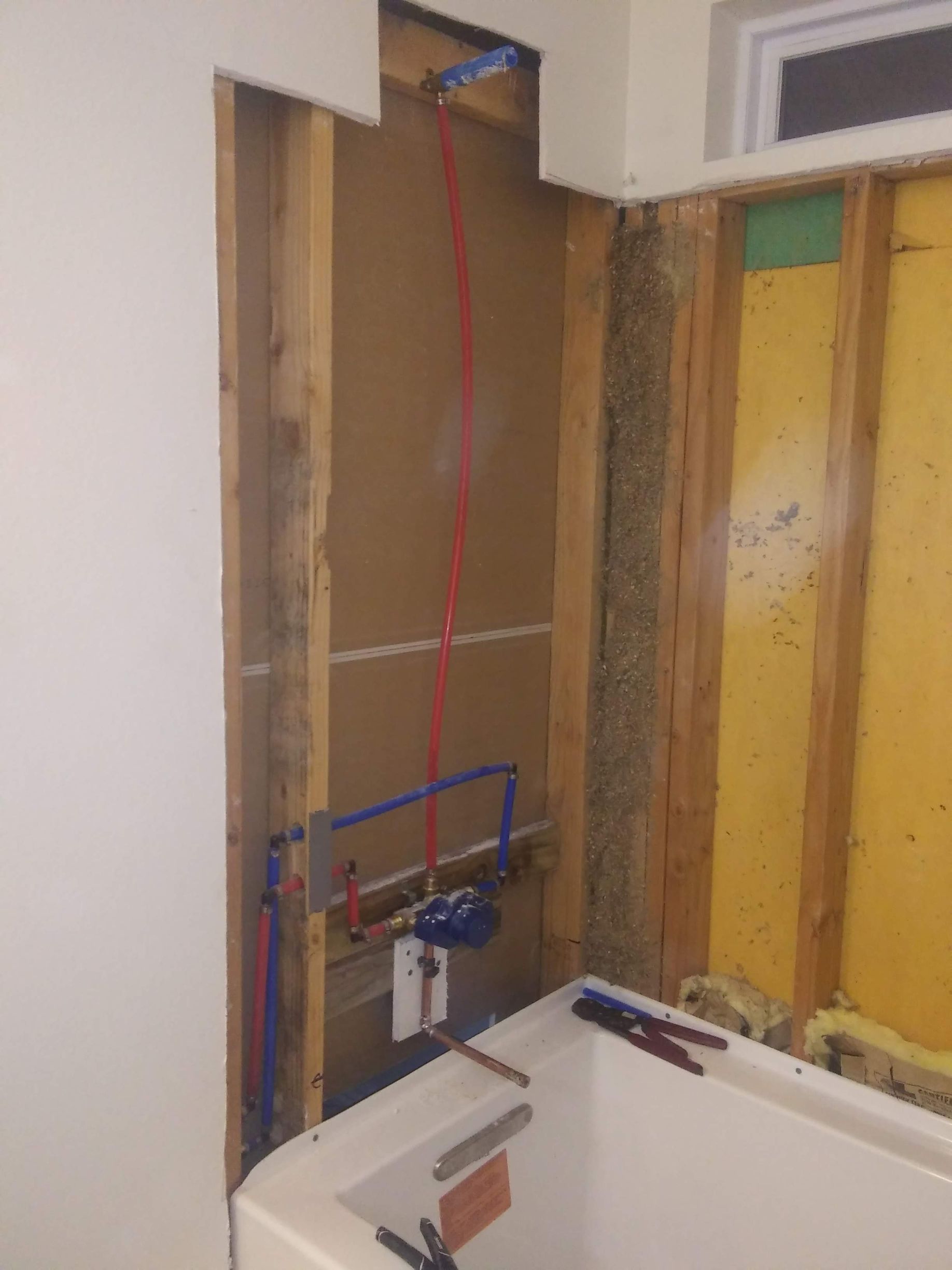 A bathroom under construction with a bathtub and a window.