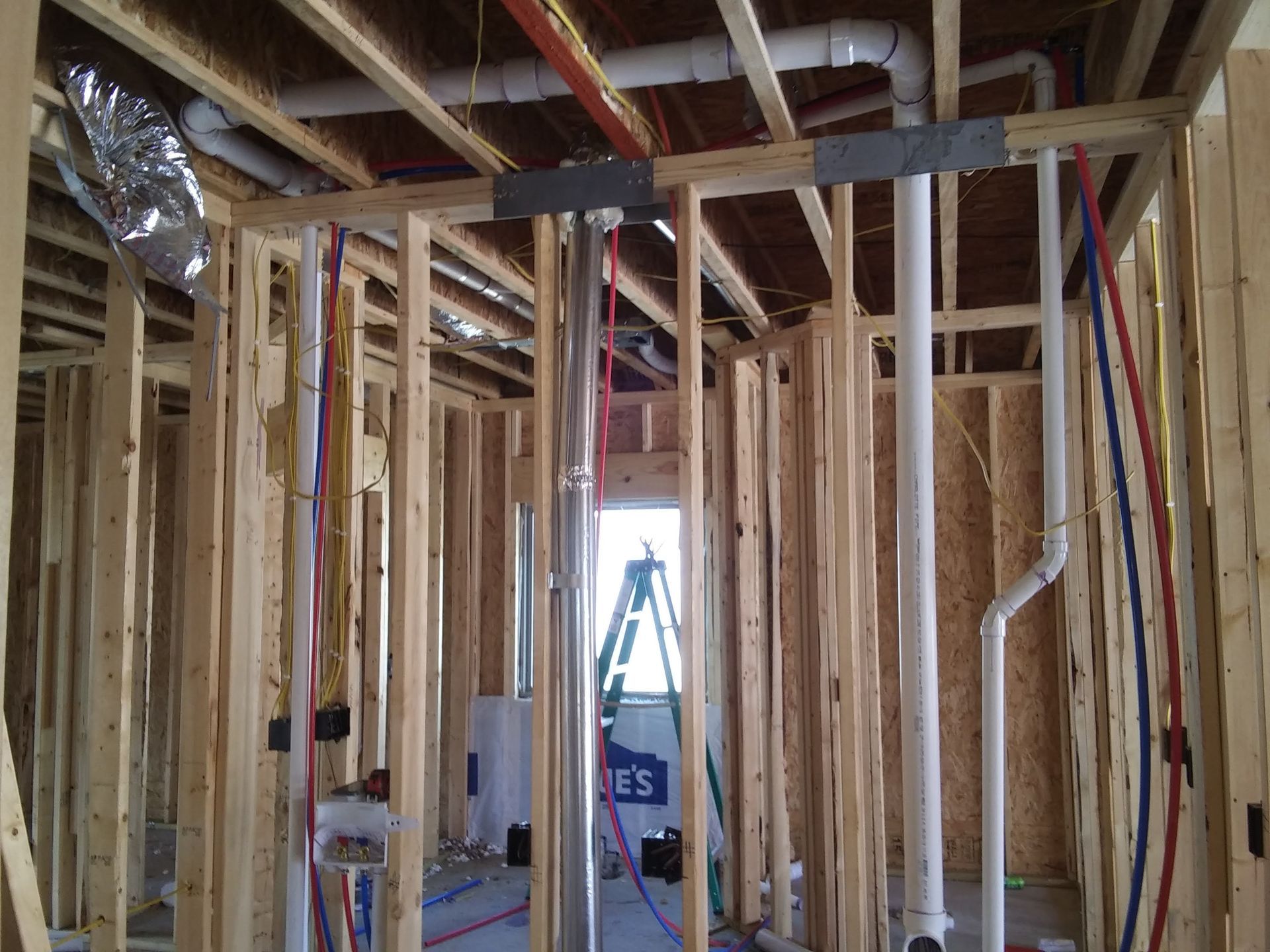 The inside of a house under construction with pipes and wires.