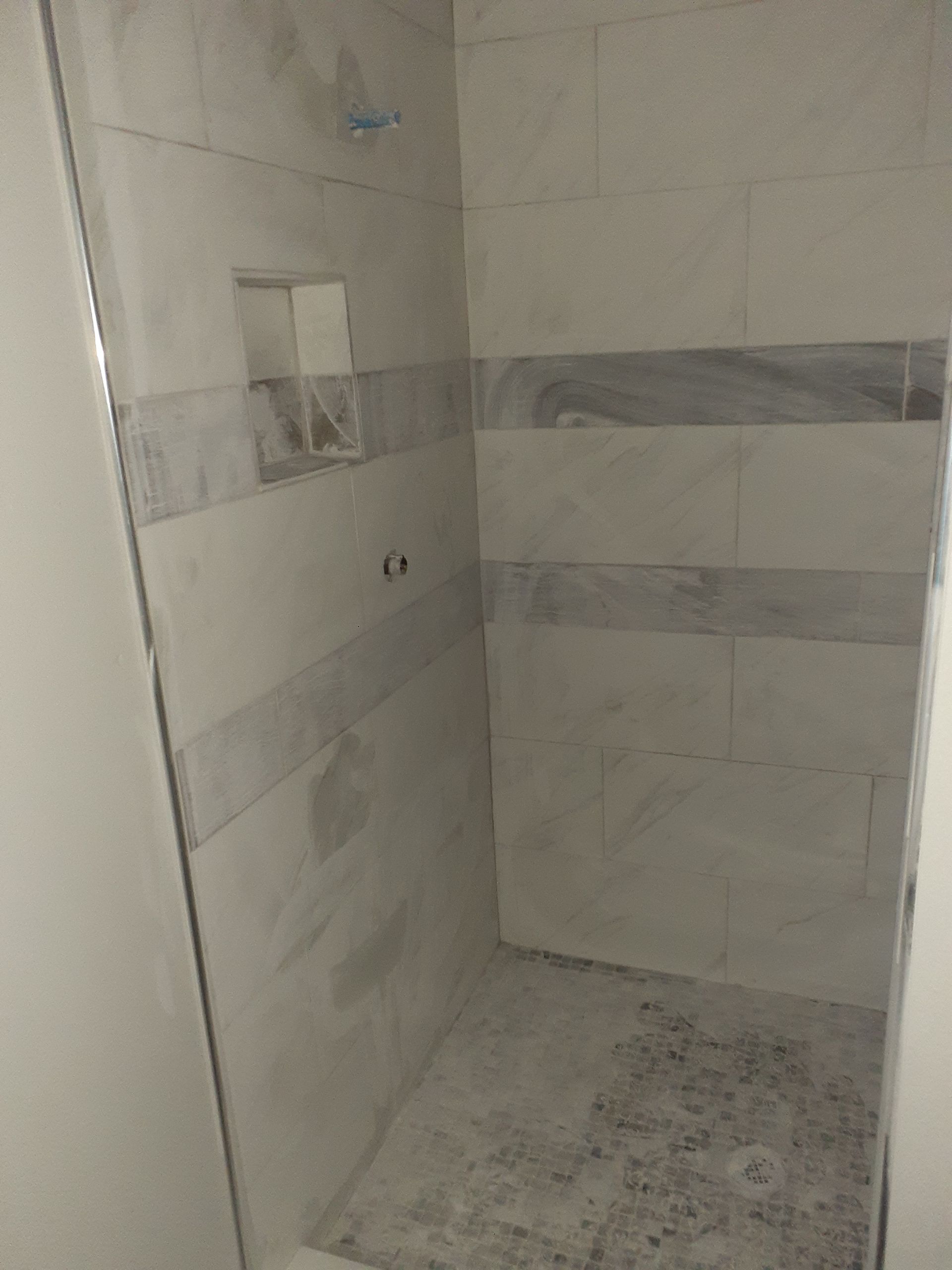 A bathroom with a walk in shower and a glass door.