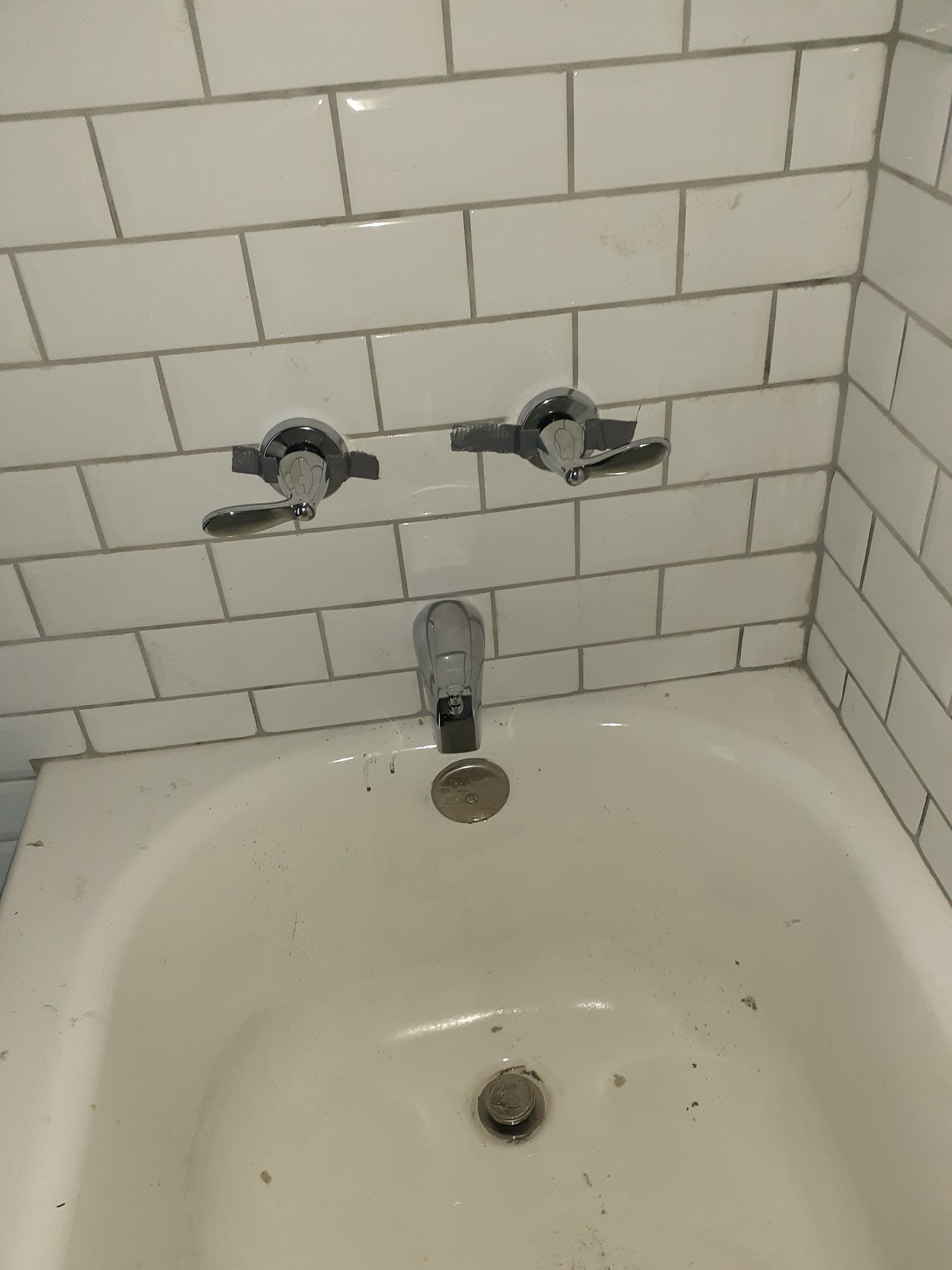 A bathtub in a bathroom with white tiles and a faucet.