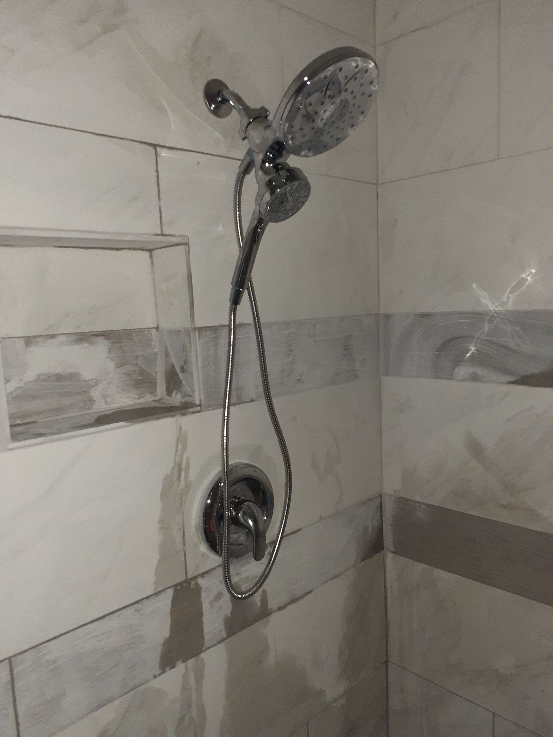 A shower head is hanging from the wall in a bathroom.