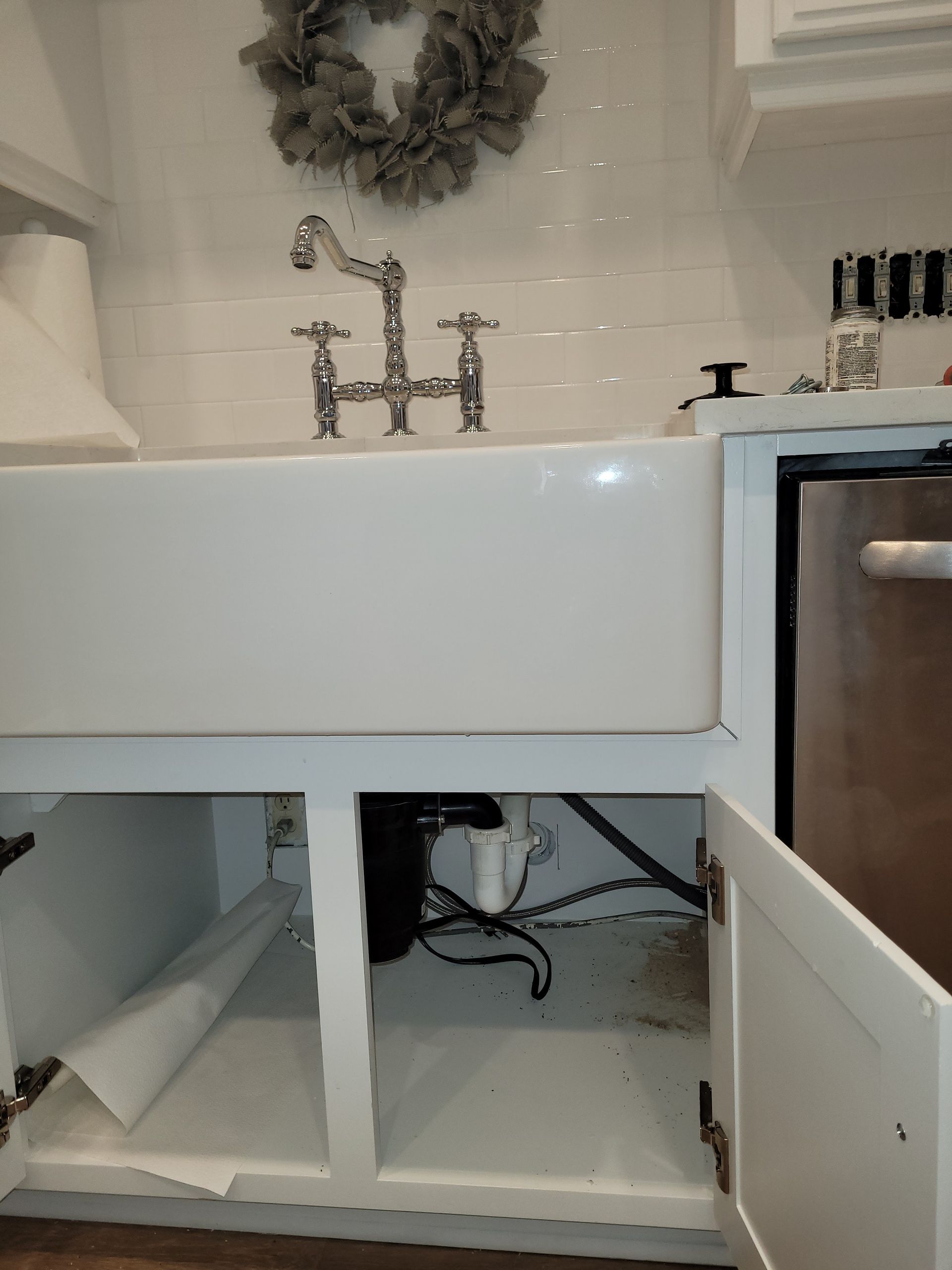 A kitchen sink with a wreath on the wall above it