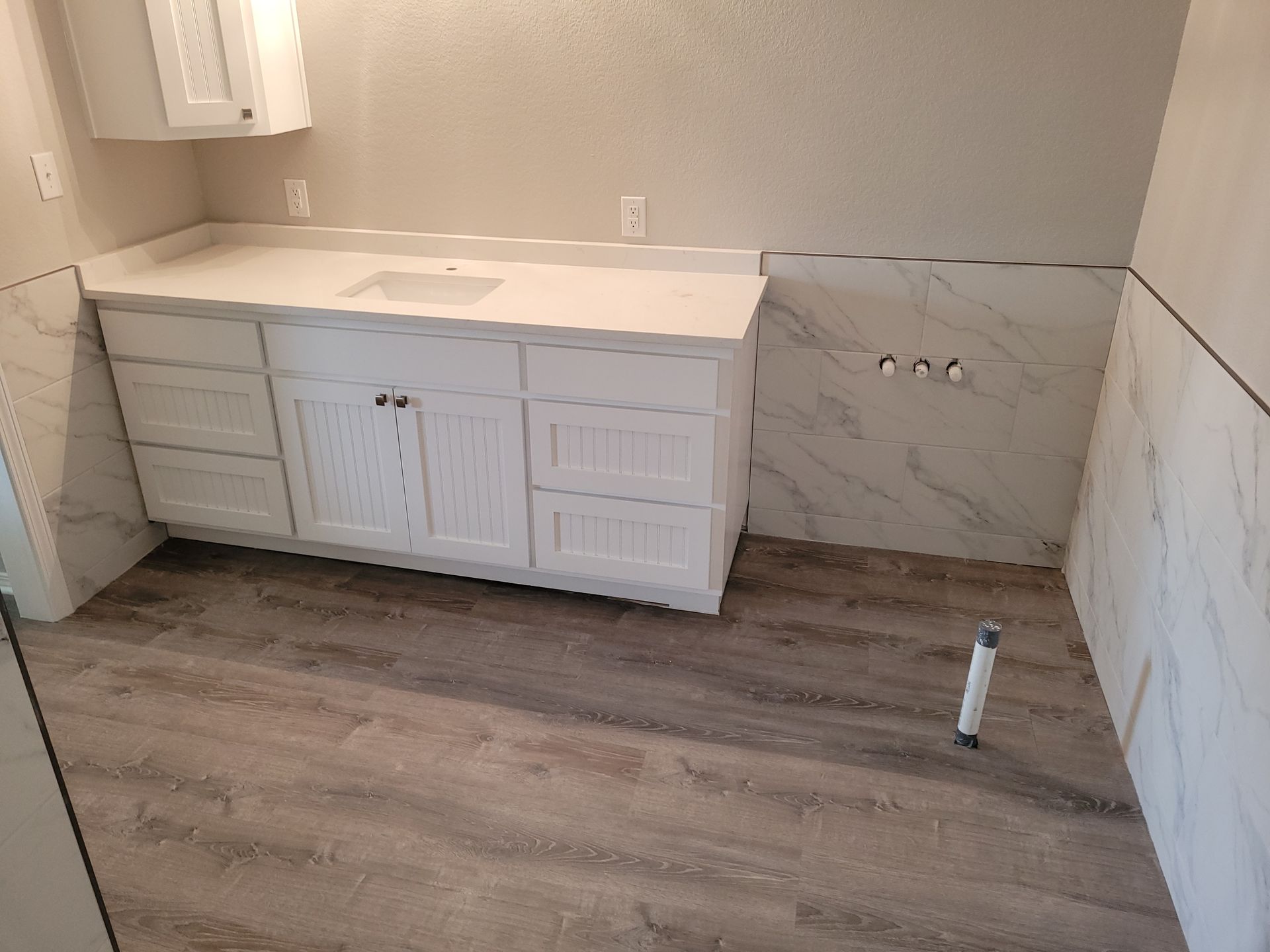 A bathroom with a sink , cabinets , and a wooden floor.
