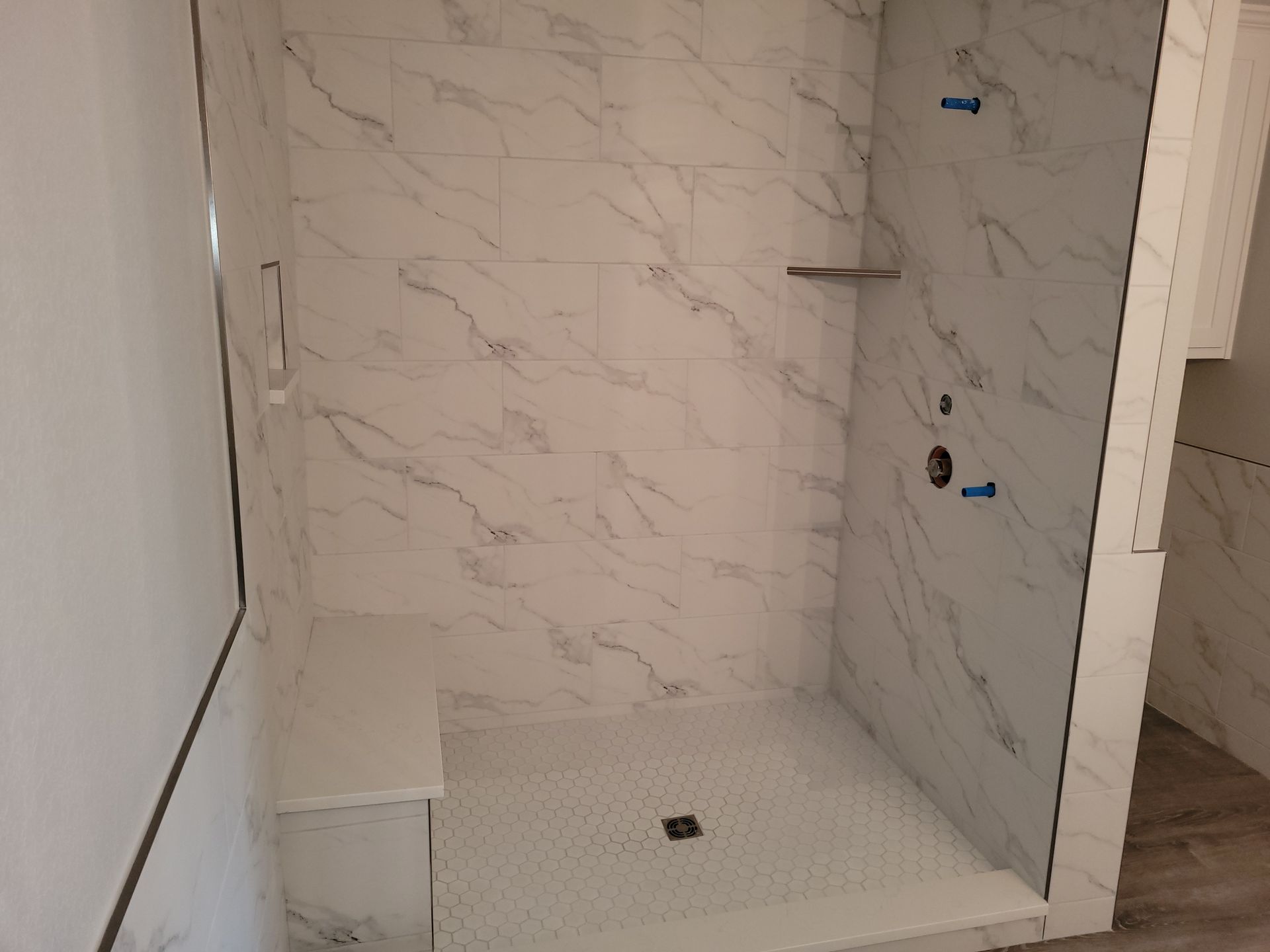 A bathroom with marble tiles and a walk in shower.