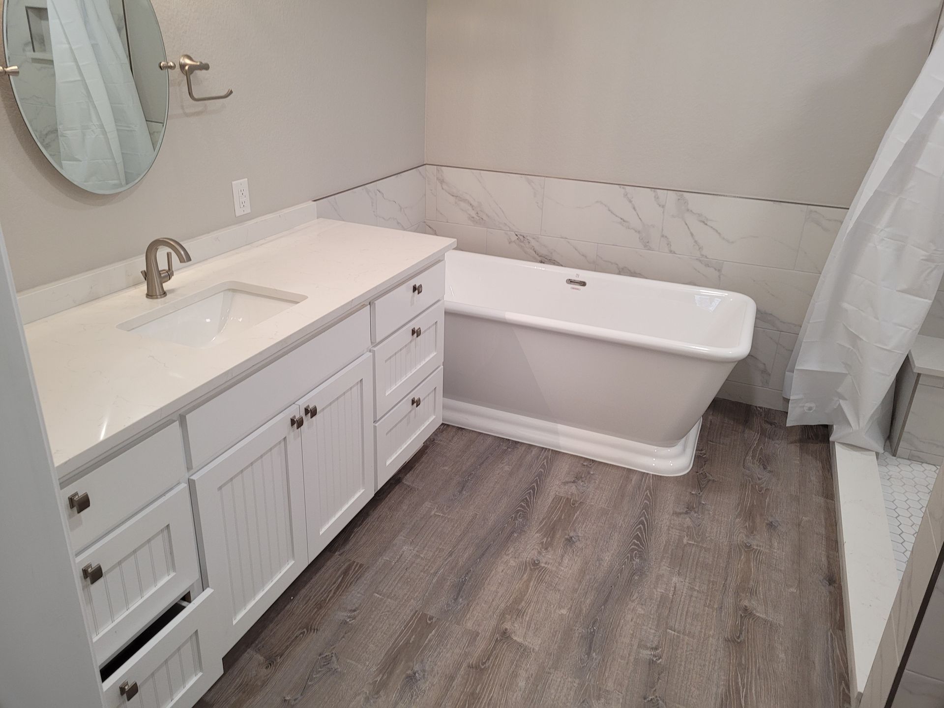 A bathroom with a tub , sink and mirror.