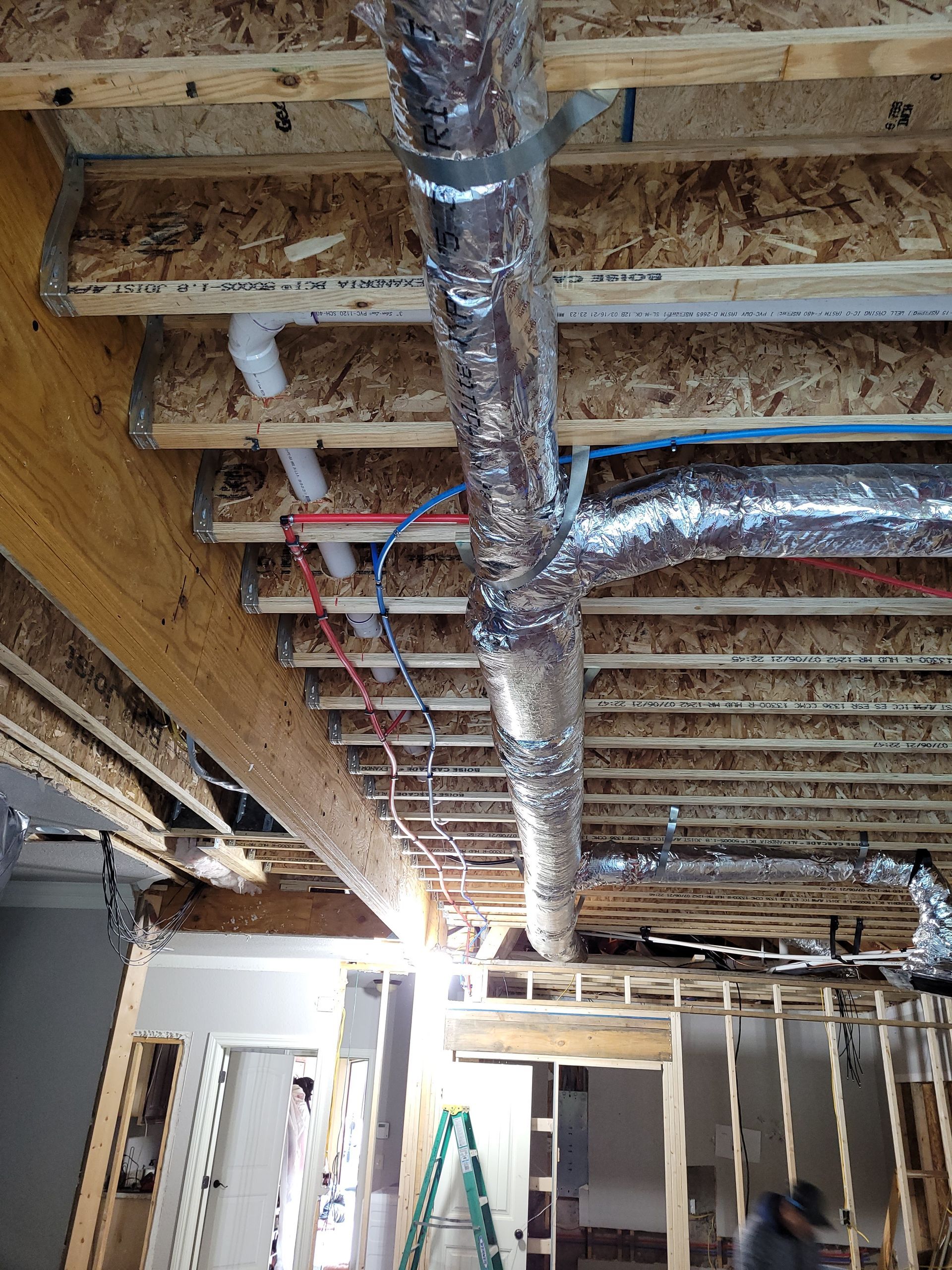A man is standing on a ladder in a room under construction.
