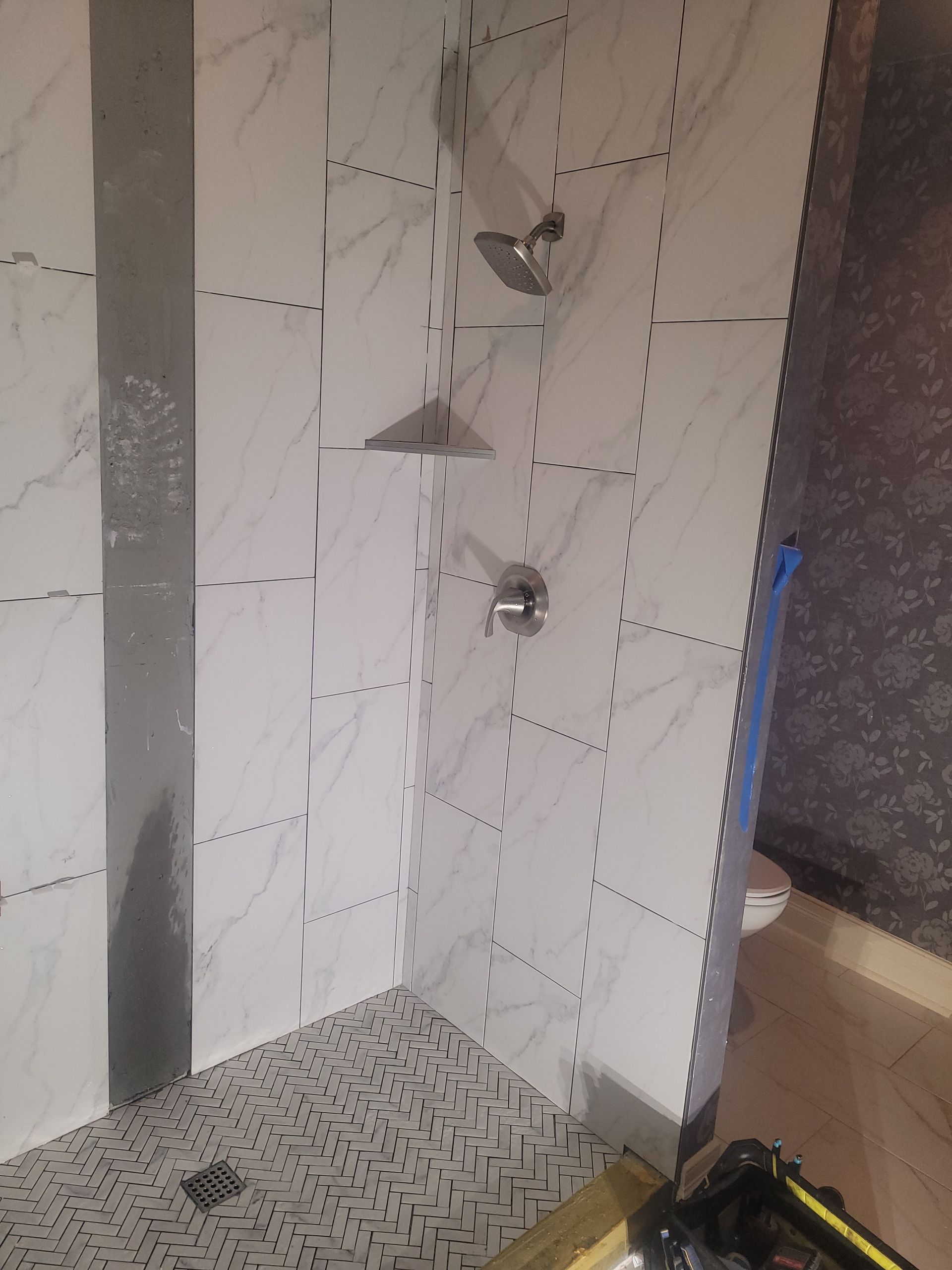 A bathroom with white tiles and a walk in shower.