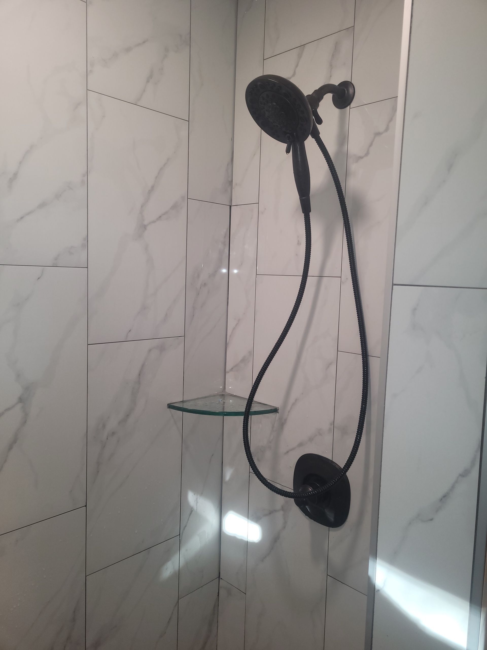 A shower head with a glass shelf attached to it