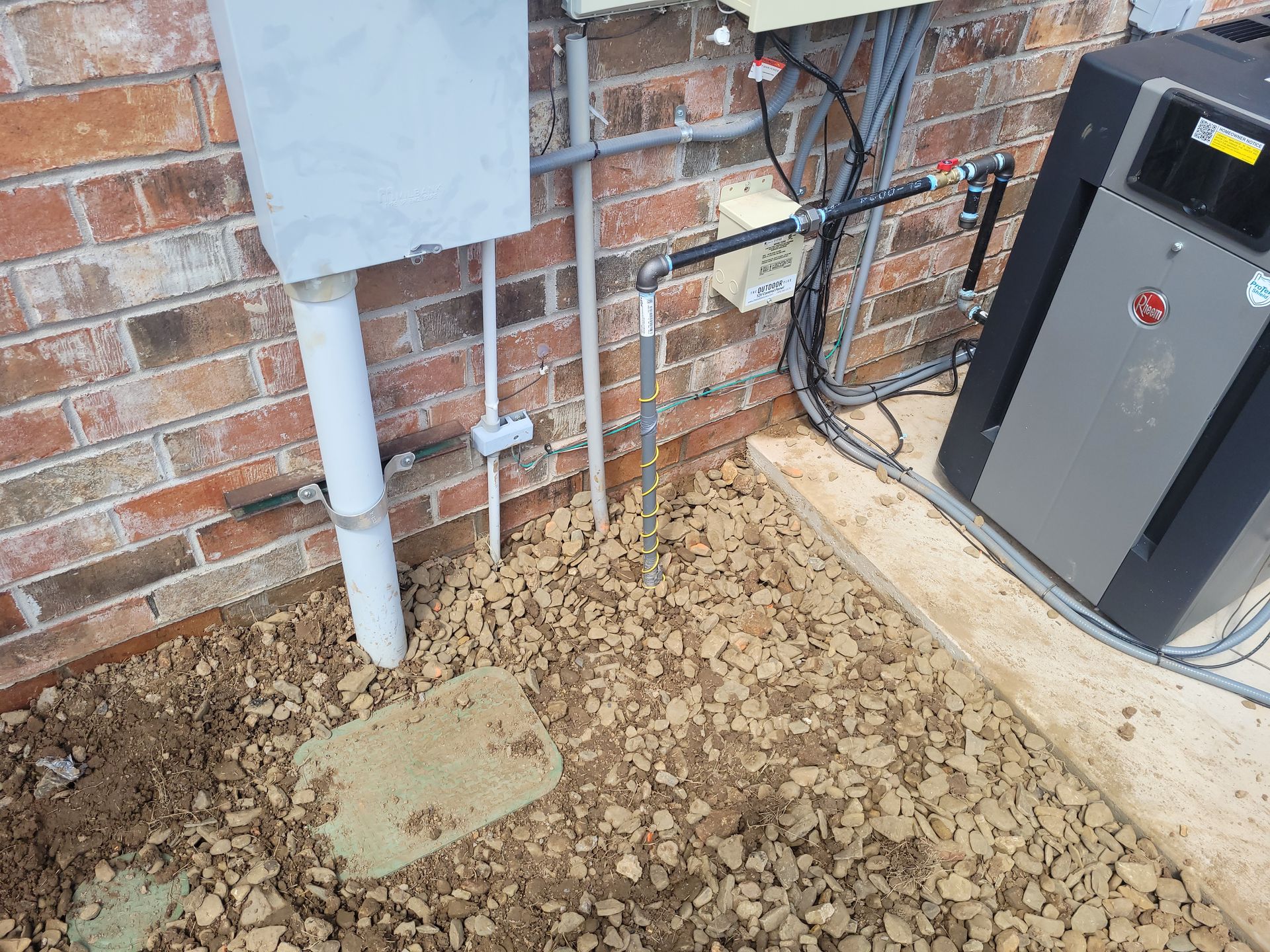 A machine is sitting on the ground next to a brick wall.