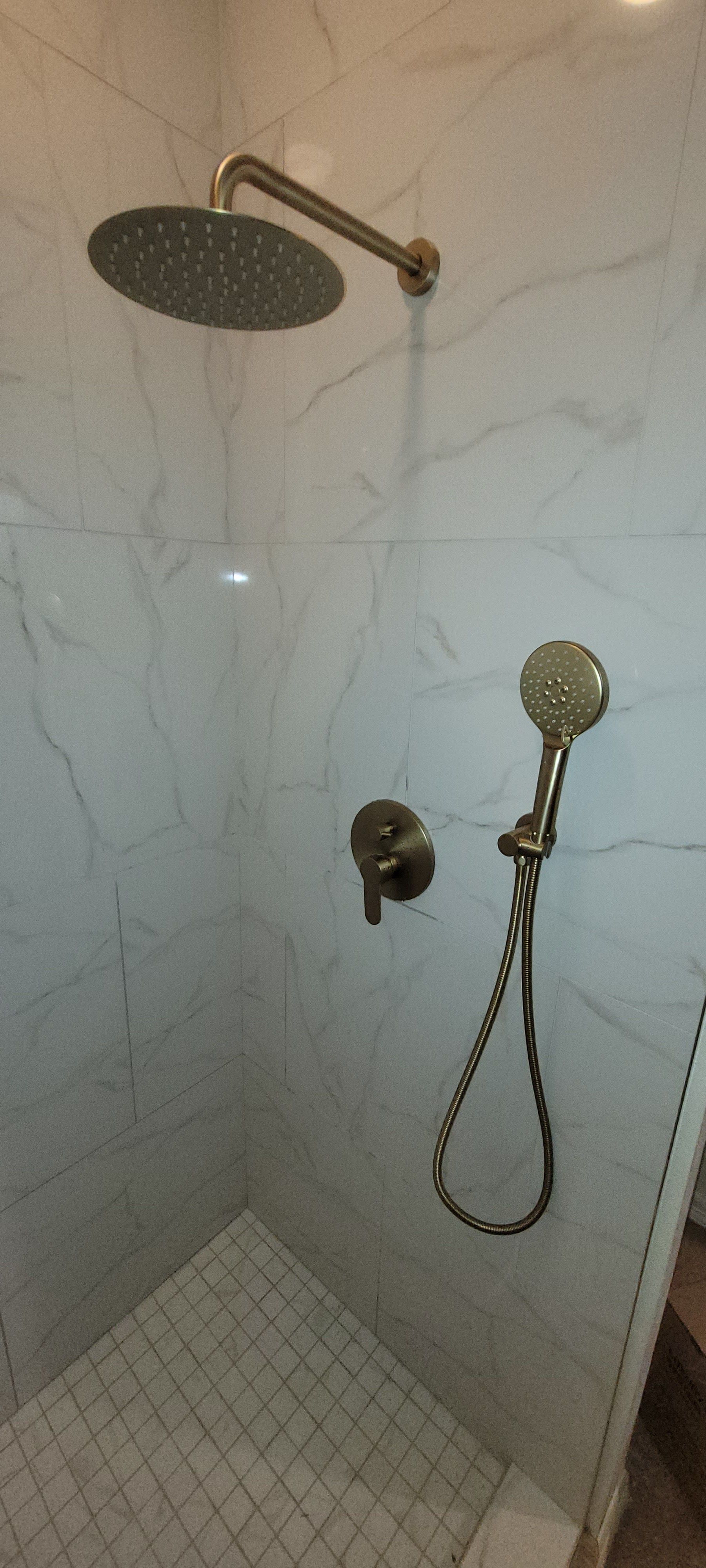 A shower with a round shower head and a handheld shower head.