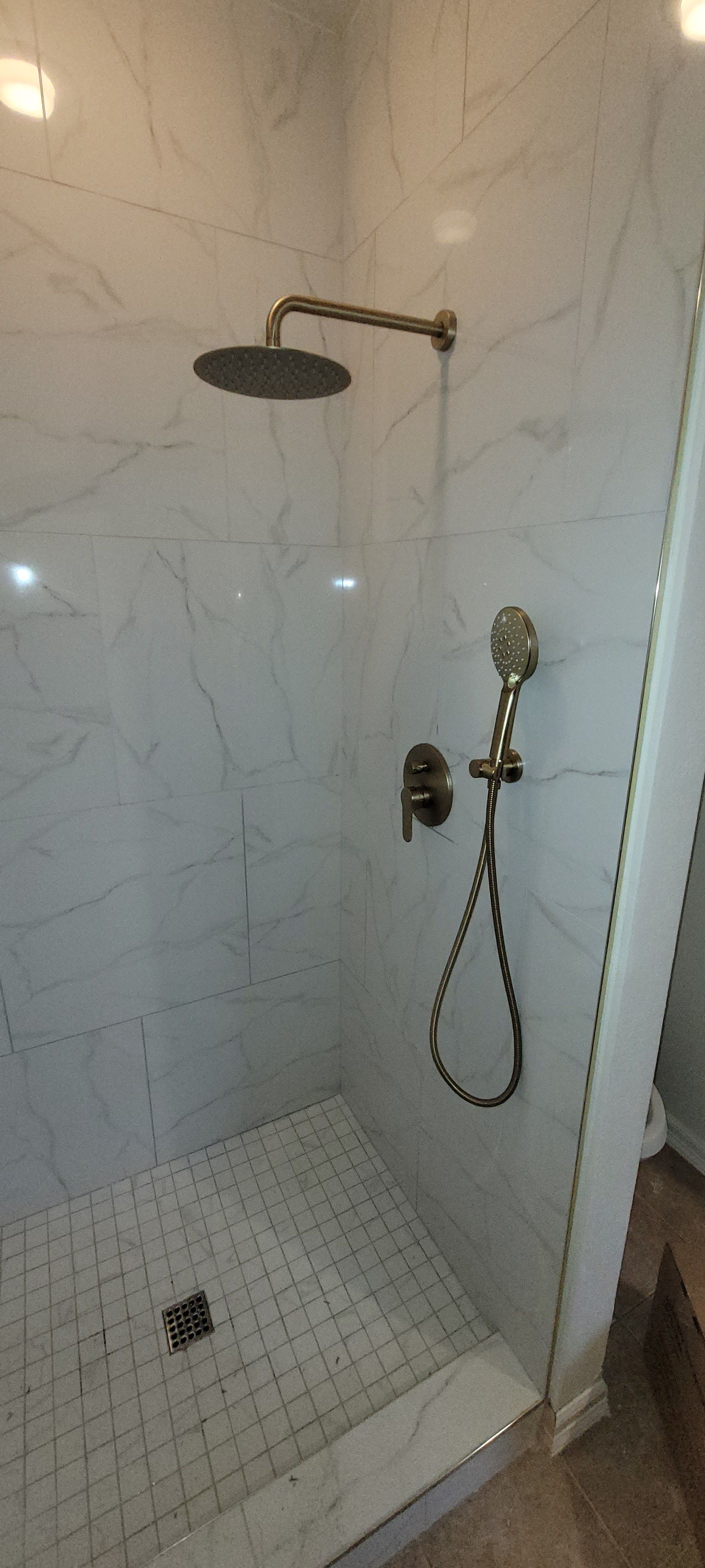 A shower stall with a shower head and hose attached to it.