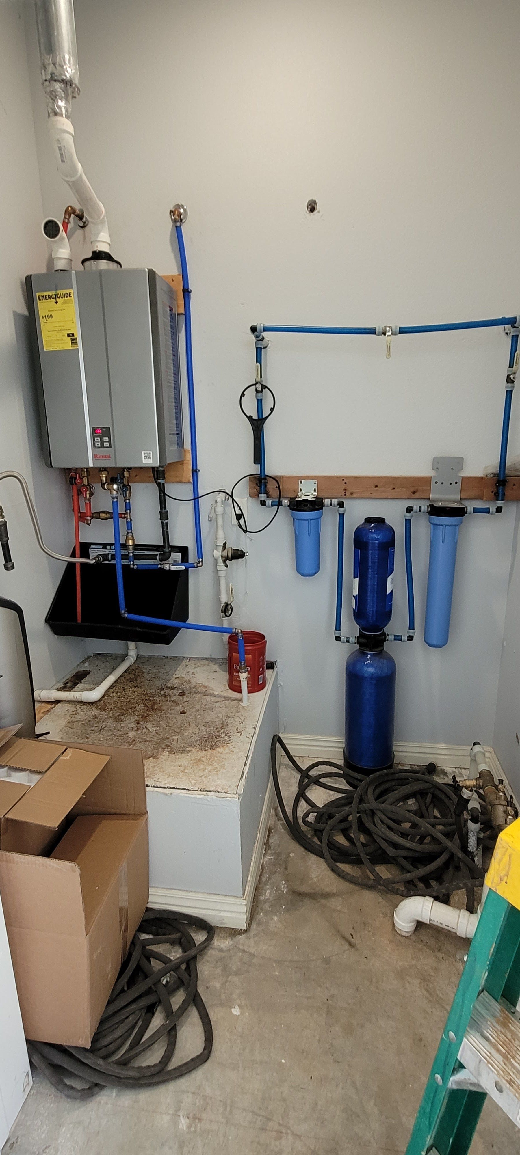 A room with a water heater and a ladder in it.