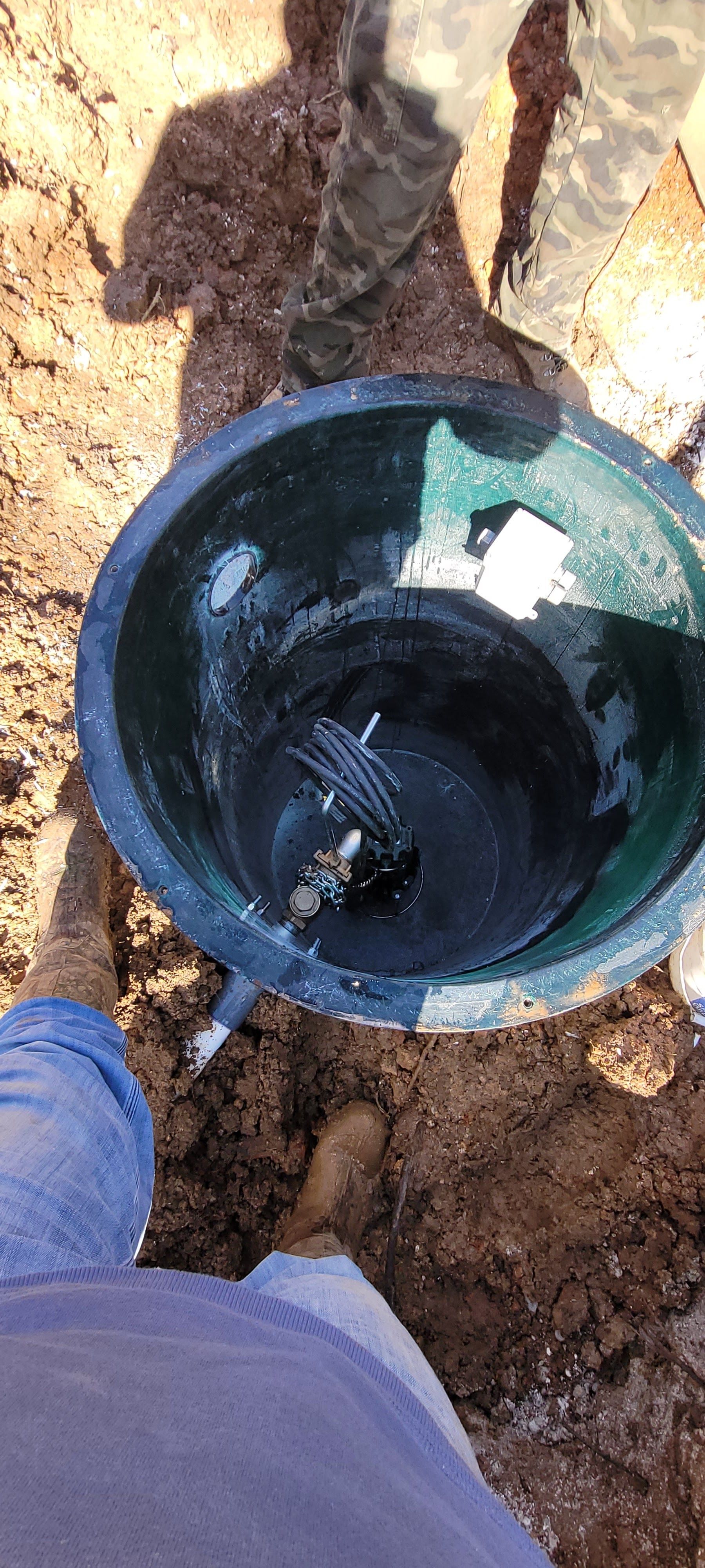 A person is standing next to a large bowl of water in the dirt.