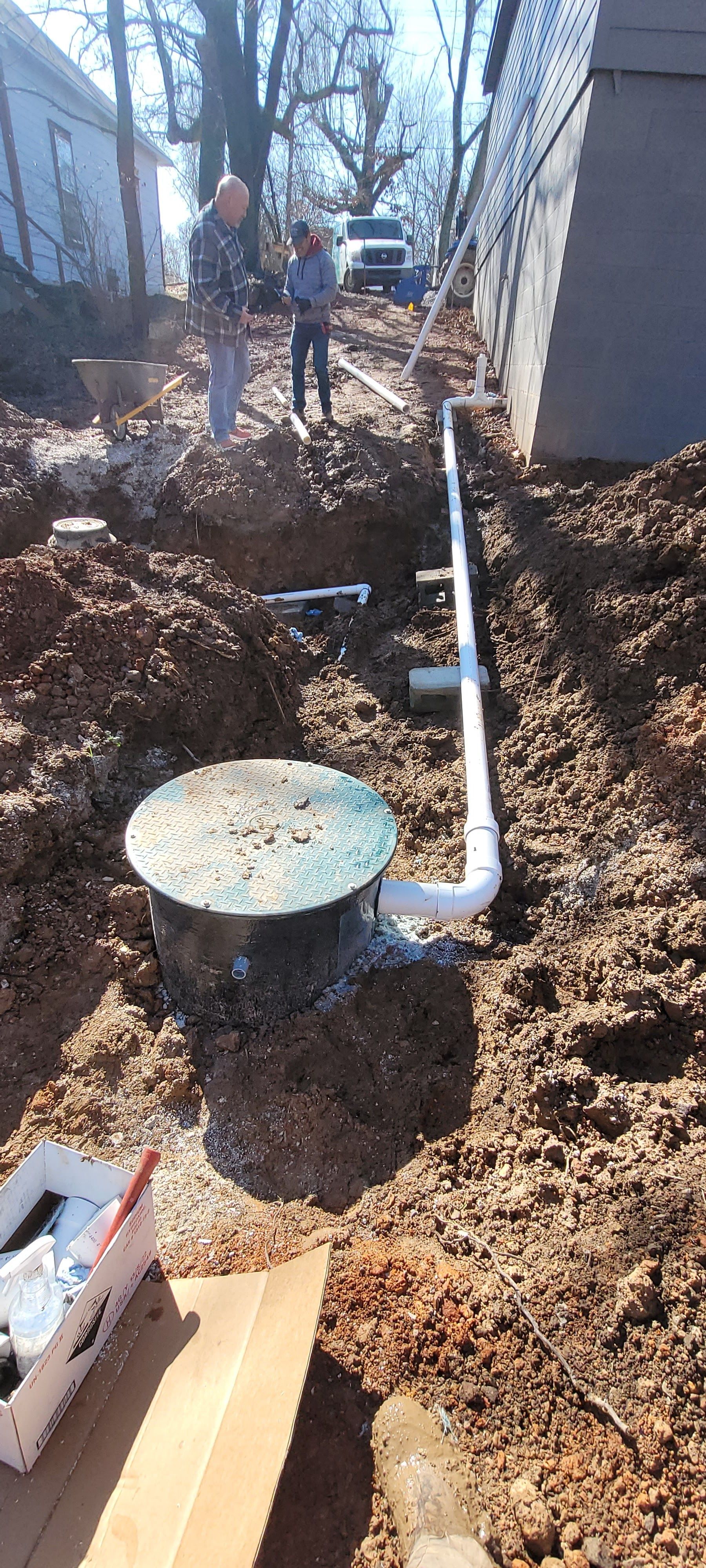 A man is digging a hole in the dirt in front of a house.