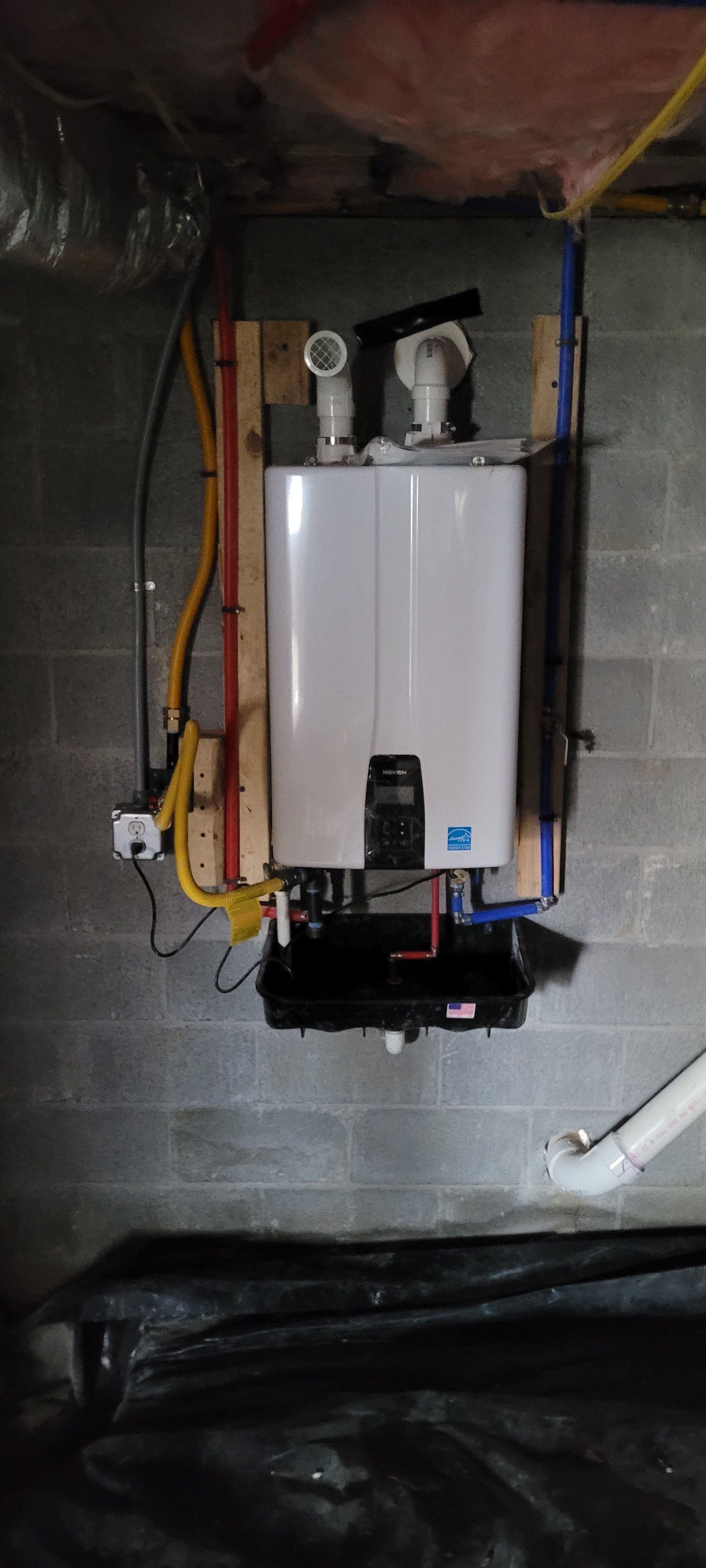 A water heater is hanging on a wall in a basement.