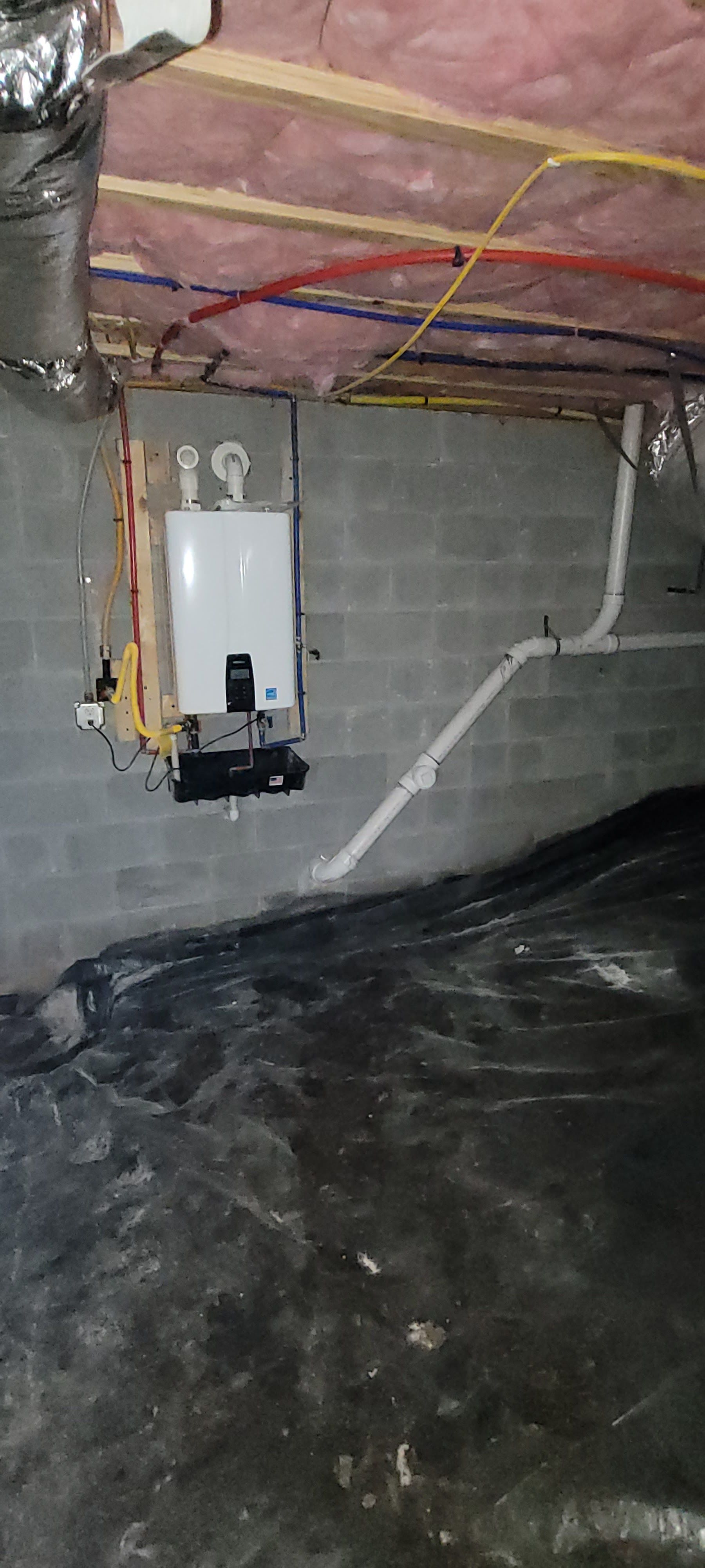 A water heater is hanging from the ceiling of a basement.