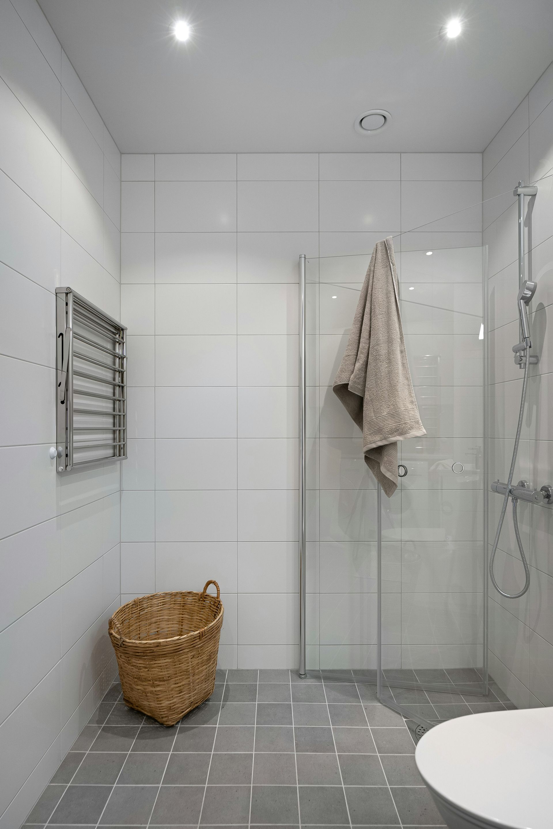 Barrier-free shower with a simple design displayed under bright modern pocket lighting making its chrome fixtures gleam.