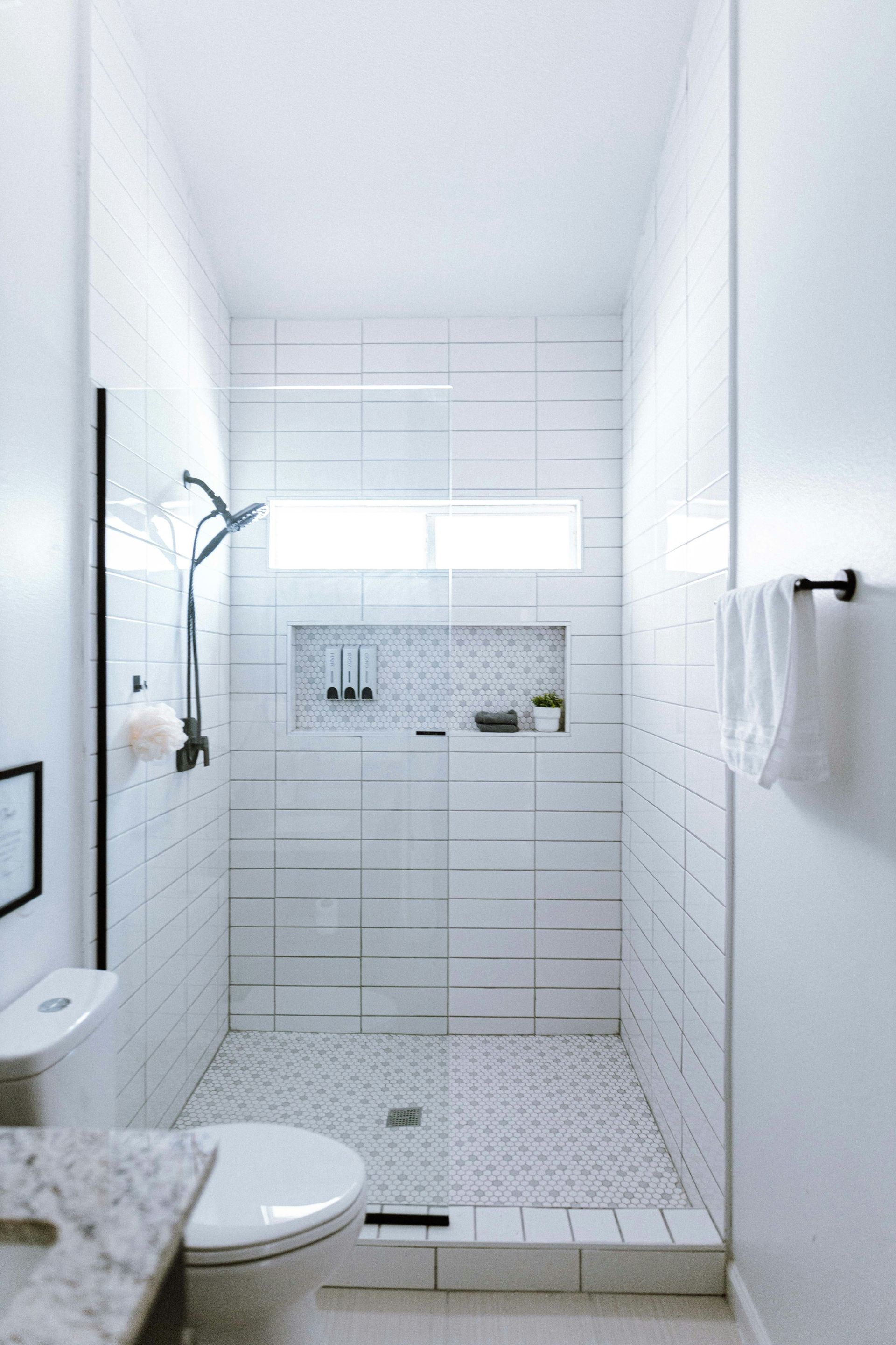 A bright white bathroom alcove with subway tiles and chrome fixtures.