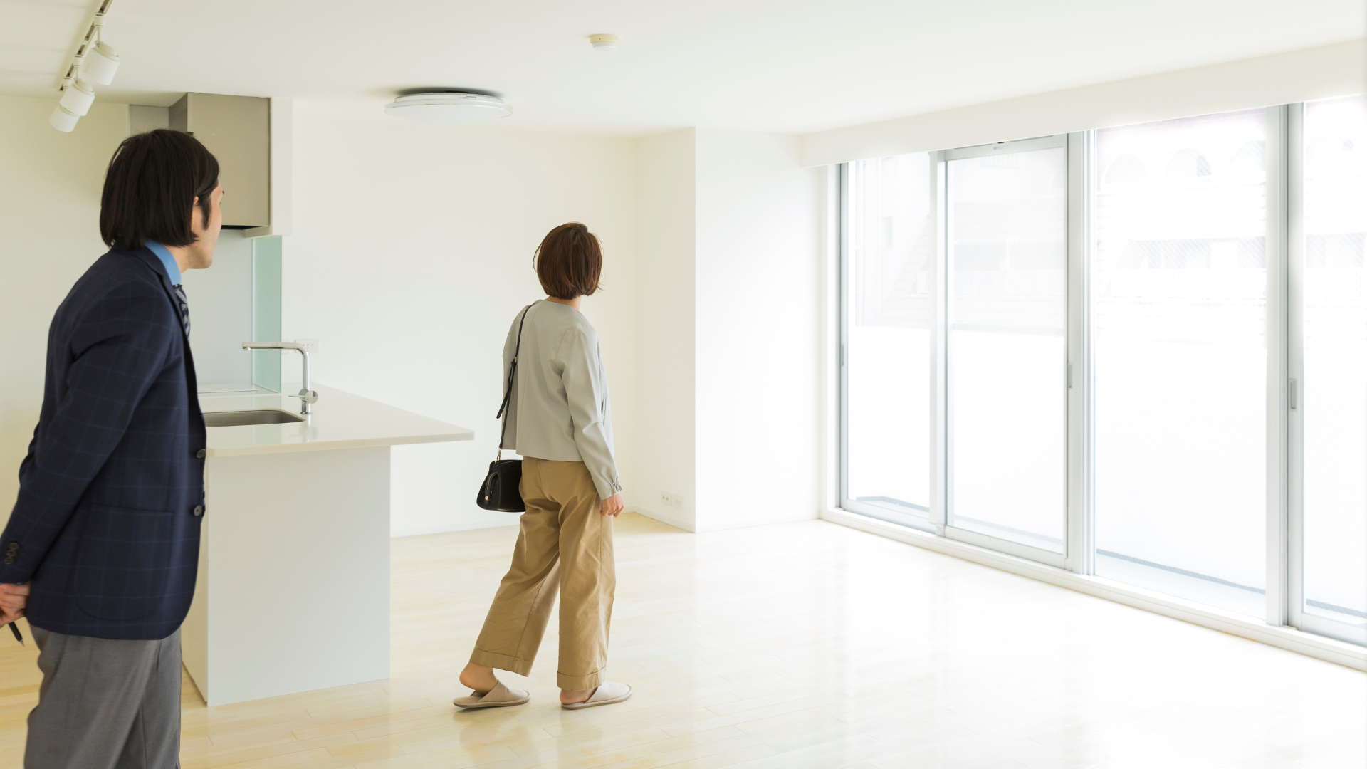 A man and a woman are walking through an empty room.