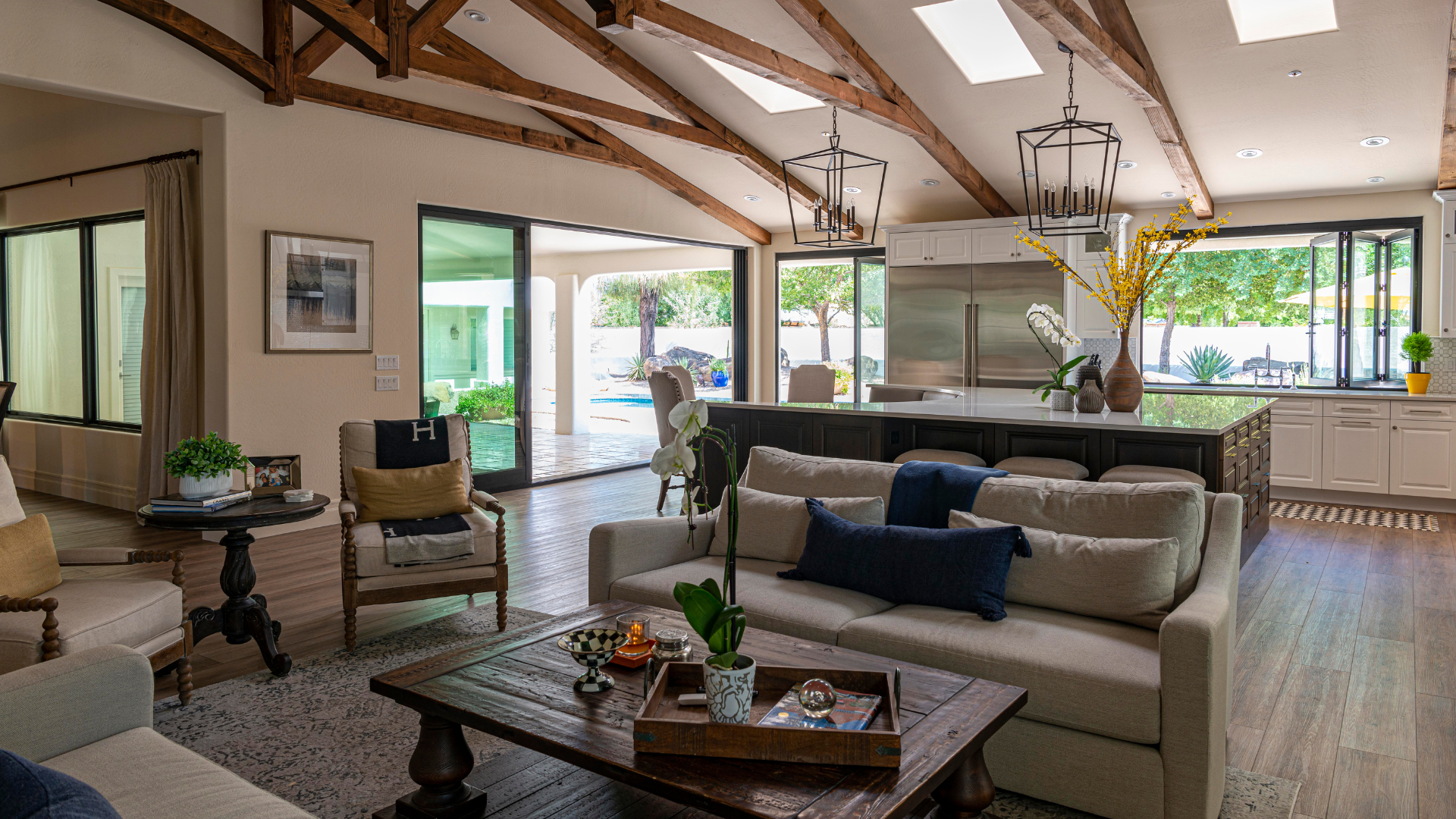 A living room with a couch , coffee table , chairs and a kitchen.