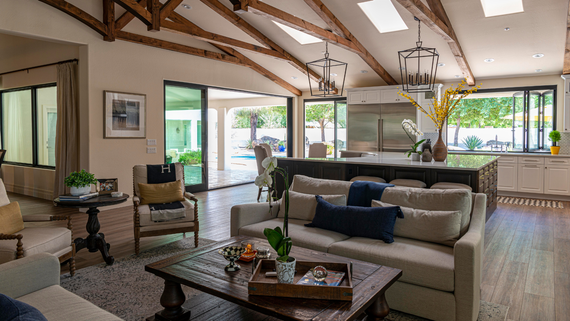 A living room with a couch , coffee table , chairs and a kitchen.