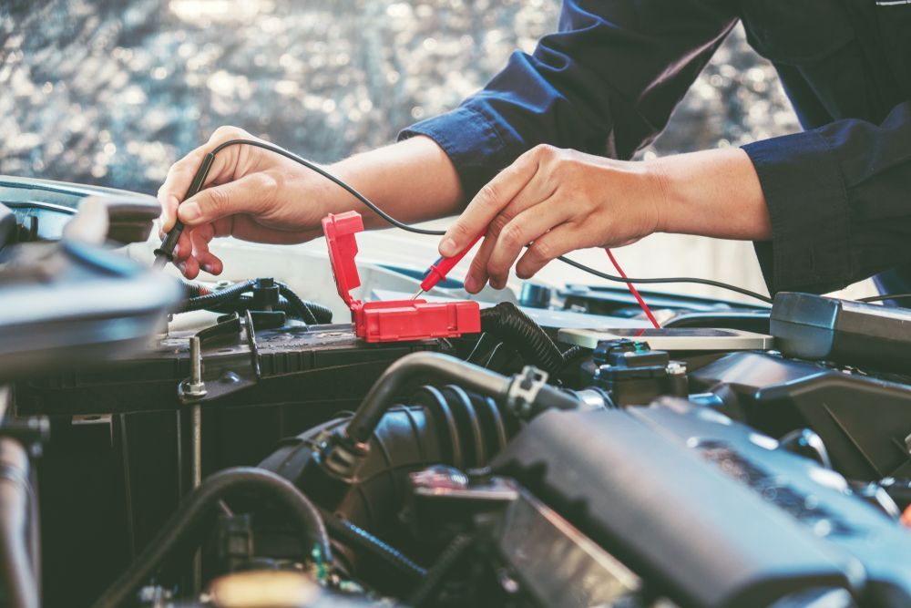 Mechanic using a multimeter on a car engine, testing electrical components. — Pete's Auto Electrical in Cranbourne, VIC