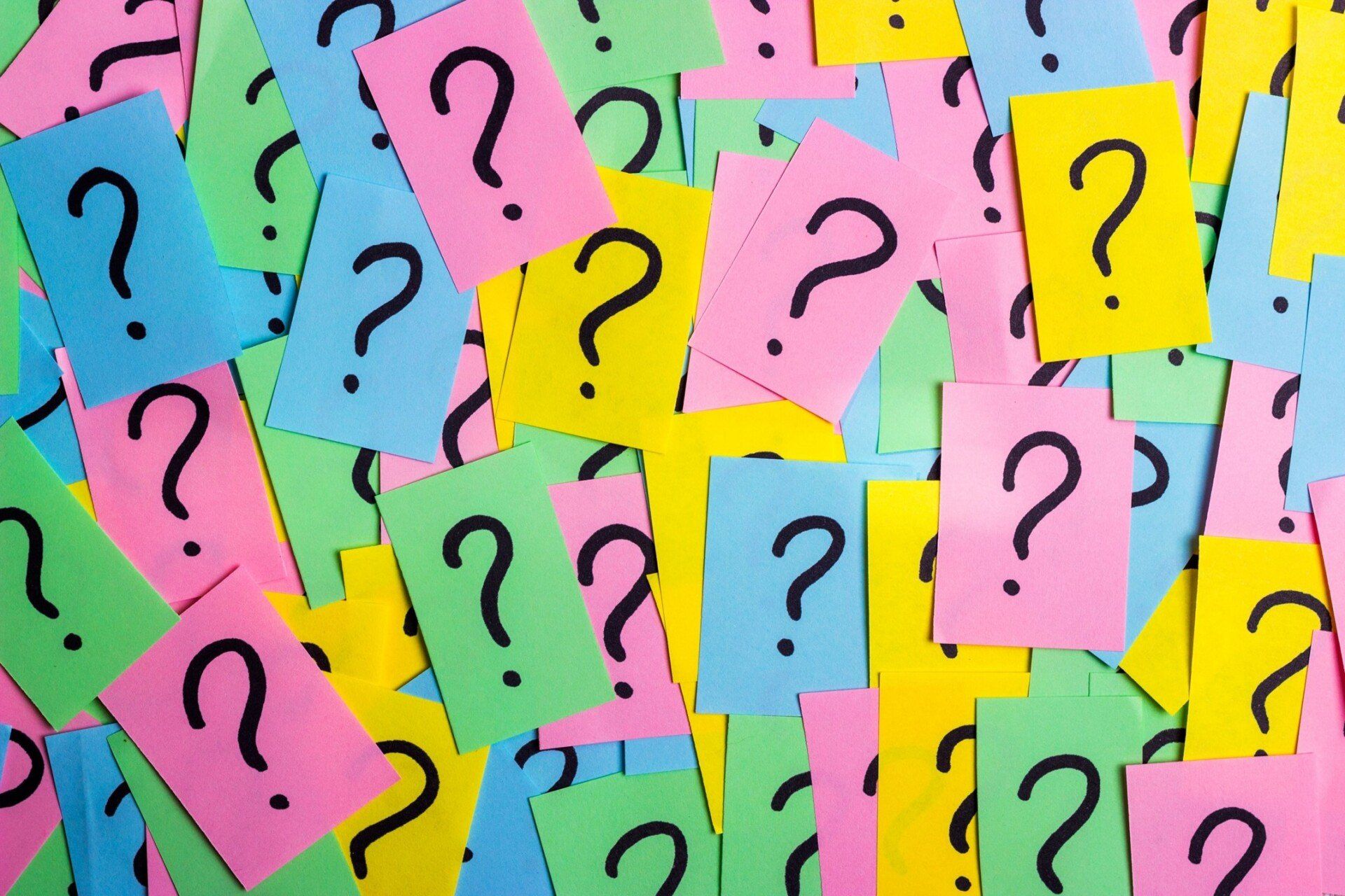 multiple overlapping and multi-colored sticky notes with question marks on the them