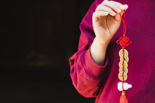 A person is holding a chinese knot and coins on a string.