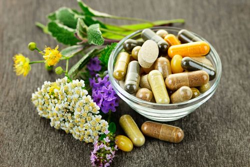 A bowl of pills and flowers on a table.