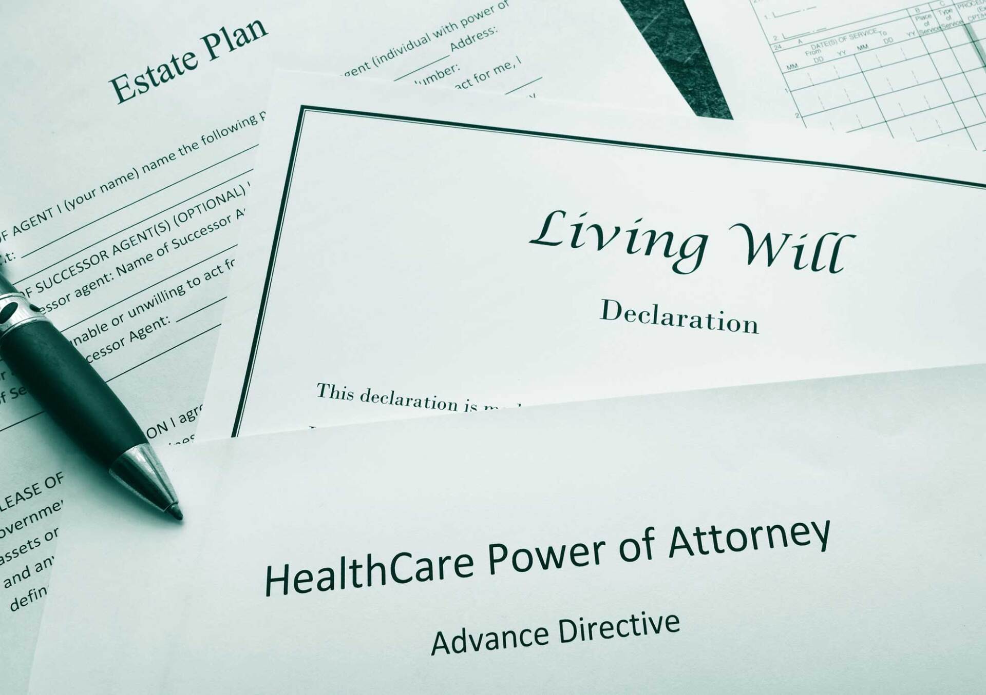 Legal documents: Estate plan, Living Will, and HealthCare Power of Attorney with a pen resting on top.