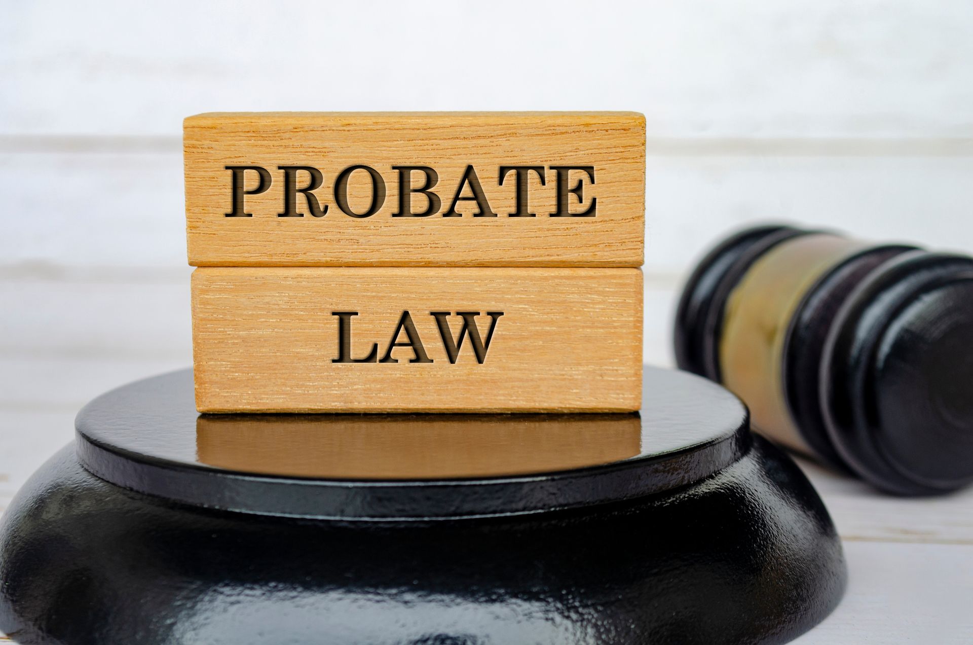 Probate Law text engraved on wooden block with blurred black gavel background. Probate Law text engraved on wooden block with blurred black gavel background.