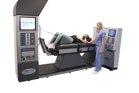 A clinician assists a patient lying on a motorized spinal decompression table equipped with digital control consoles.