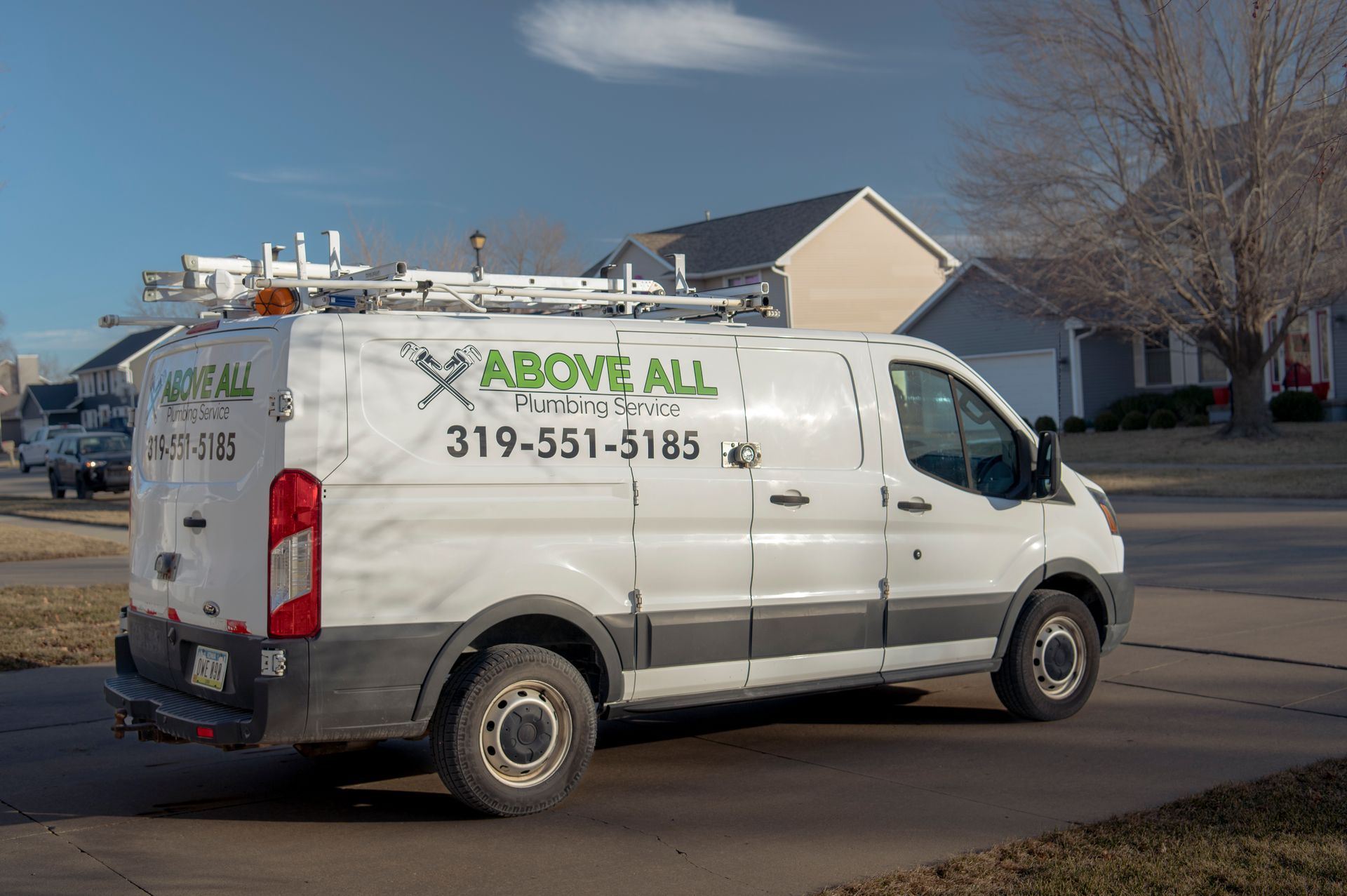 A white van is parked on the side of the road in front of a house.
